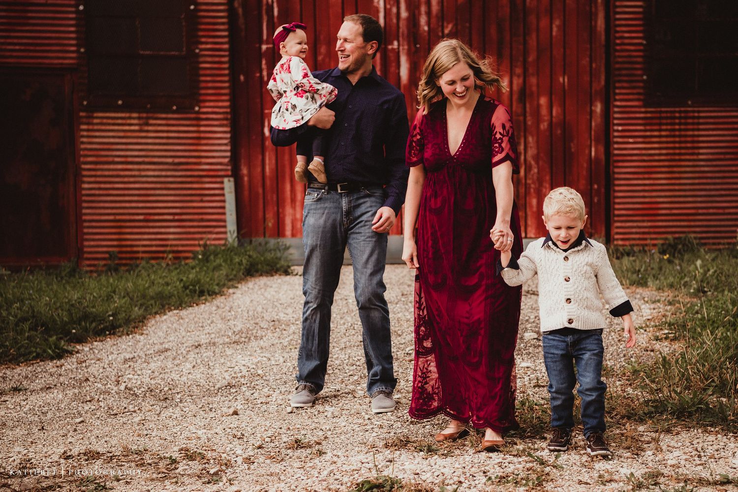 Family photo in front of a rustic red barn with flowing velvet dress.