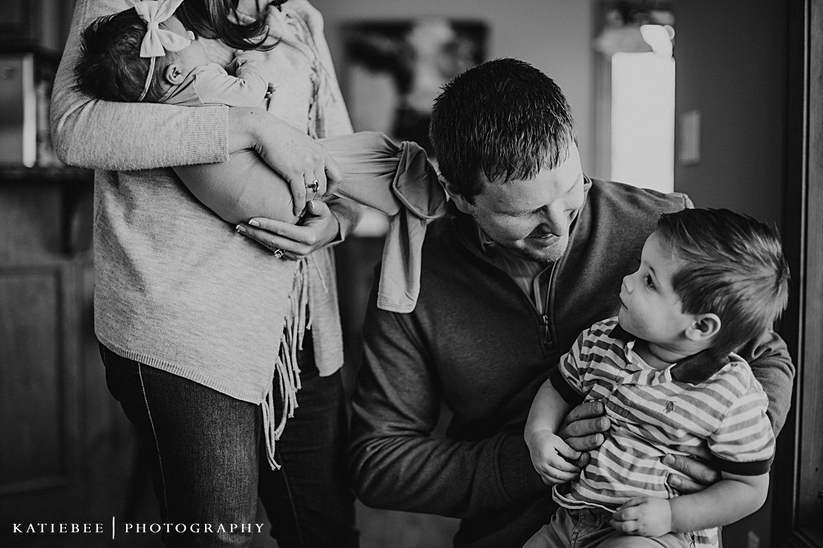 Candid black and white family photo showing playful interaction in home interior.