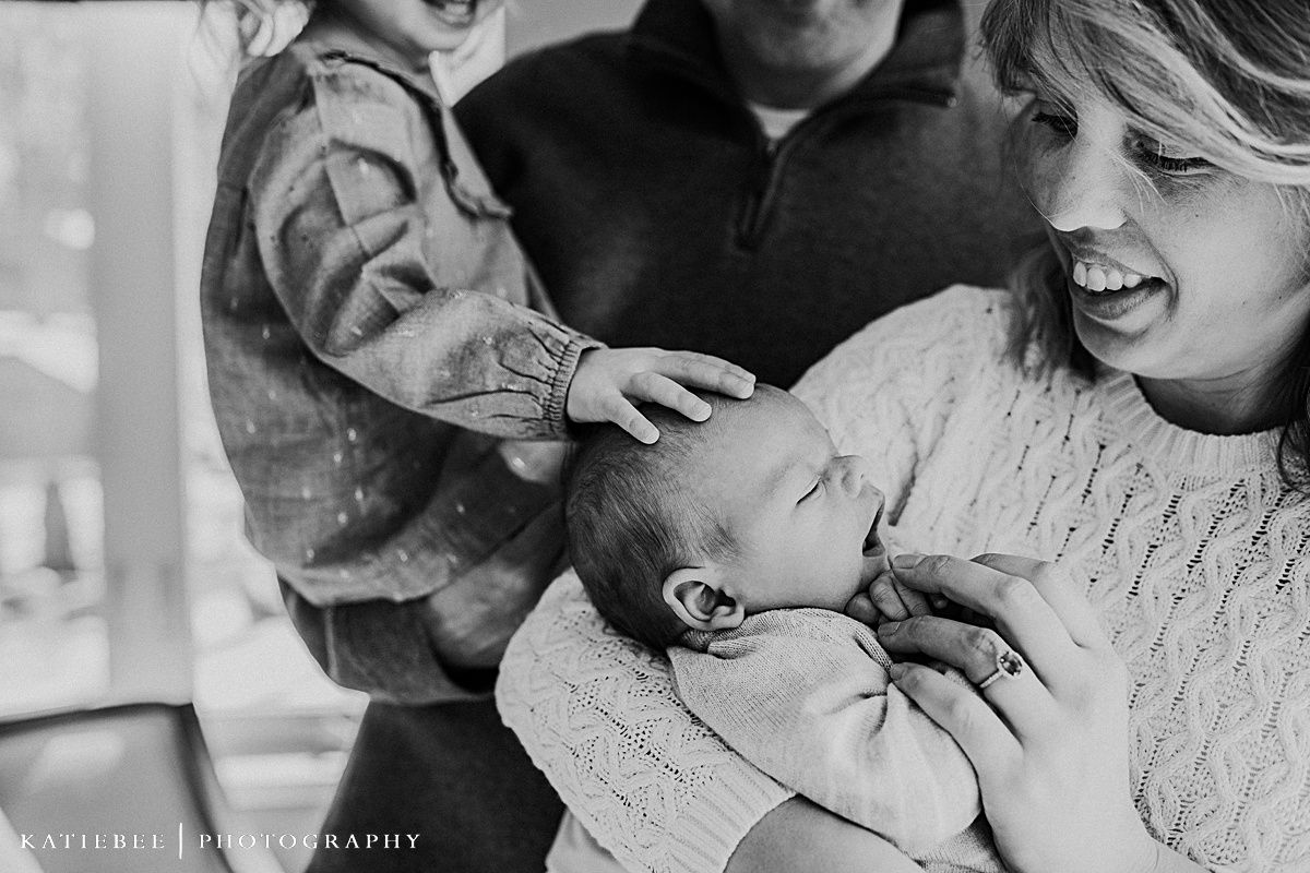 Black and white close-up shot of a family admiring their newborn baby together.
