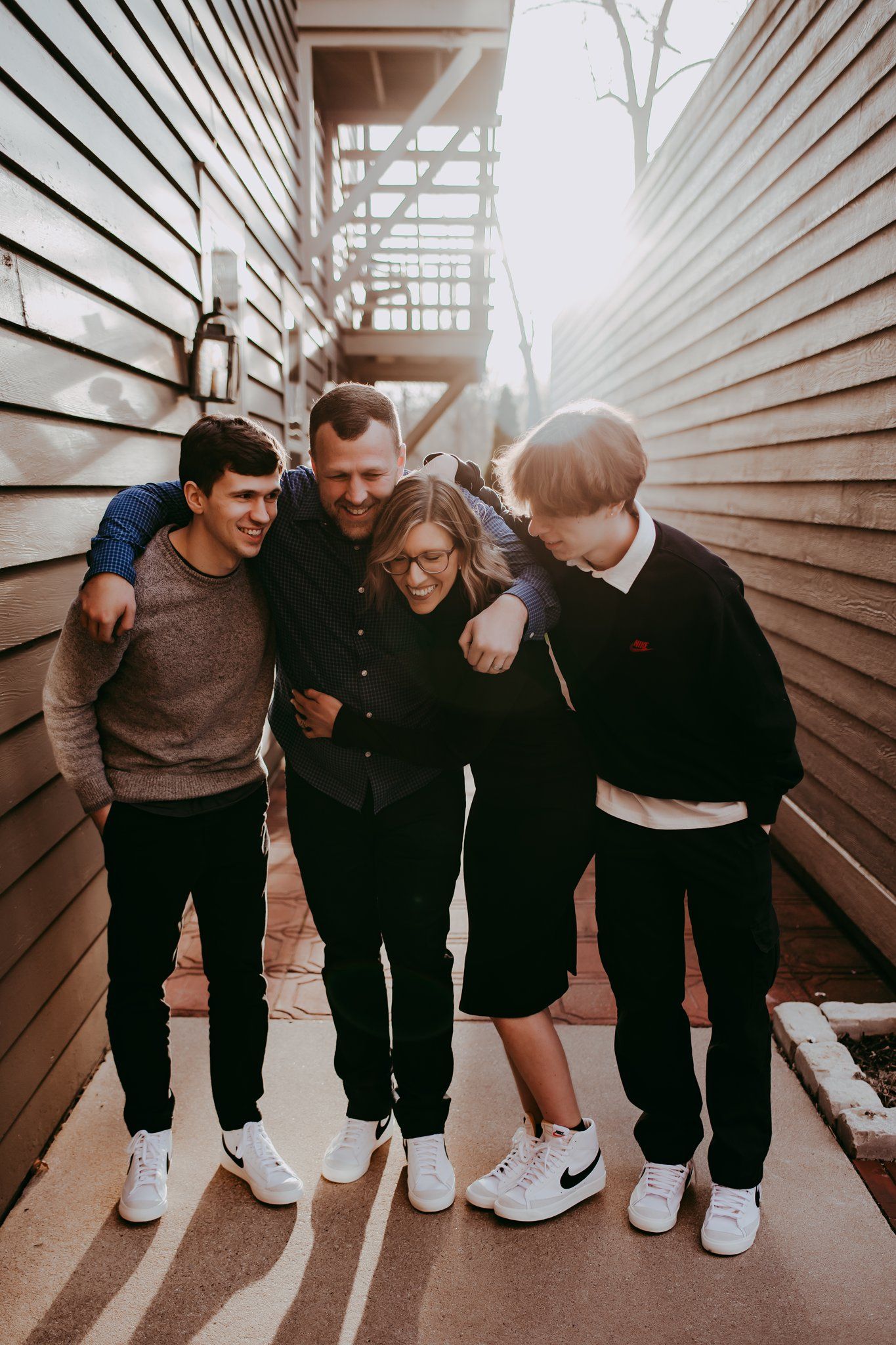 Candid group shot between wooden walls with natural sunlight filtering through.