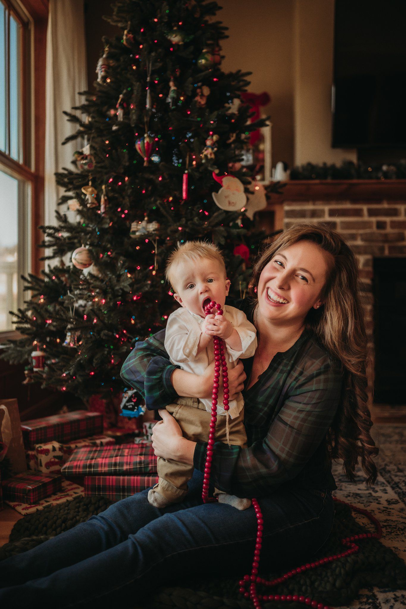 Joyful holiday moment by a decorated Christmas tree with red beaded garland.
