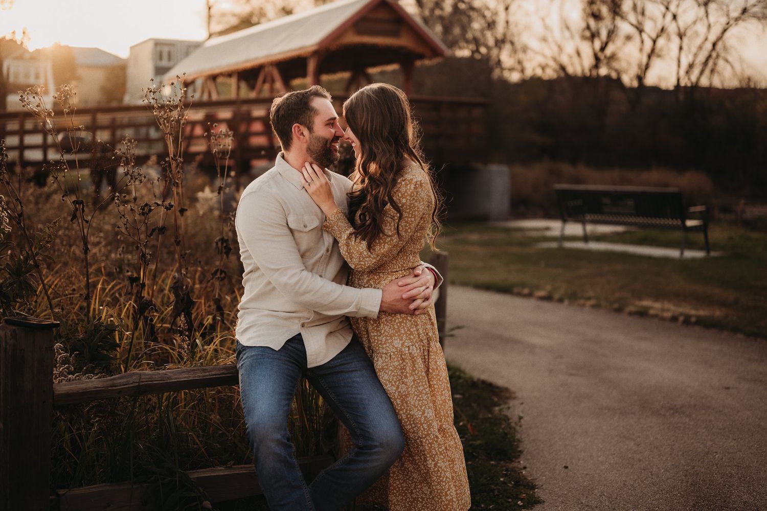 Warm sunset engagement photo of a couple sharing an intimate moment near a rustic building.