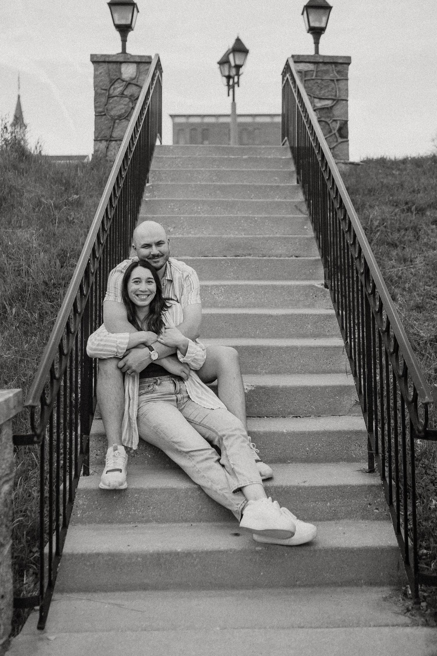 Black and white photo of a couple sitting closely together on outdoor bridge steps.