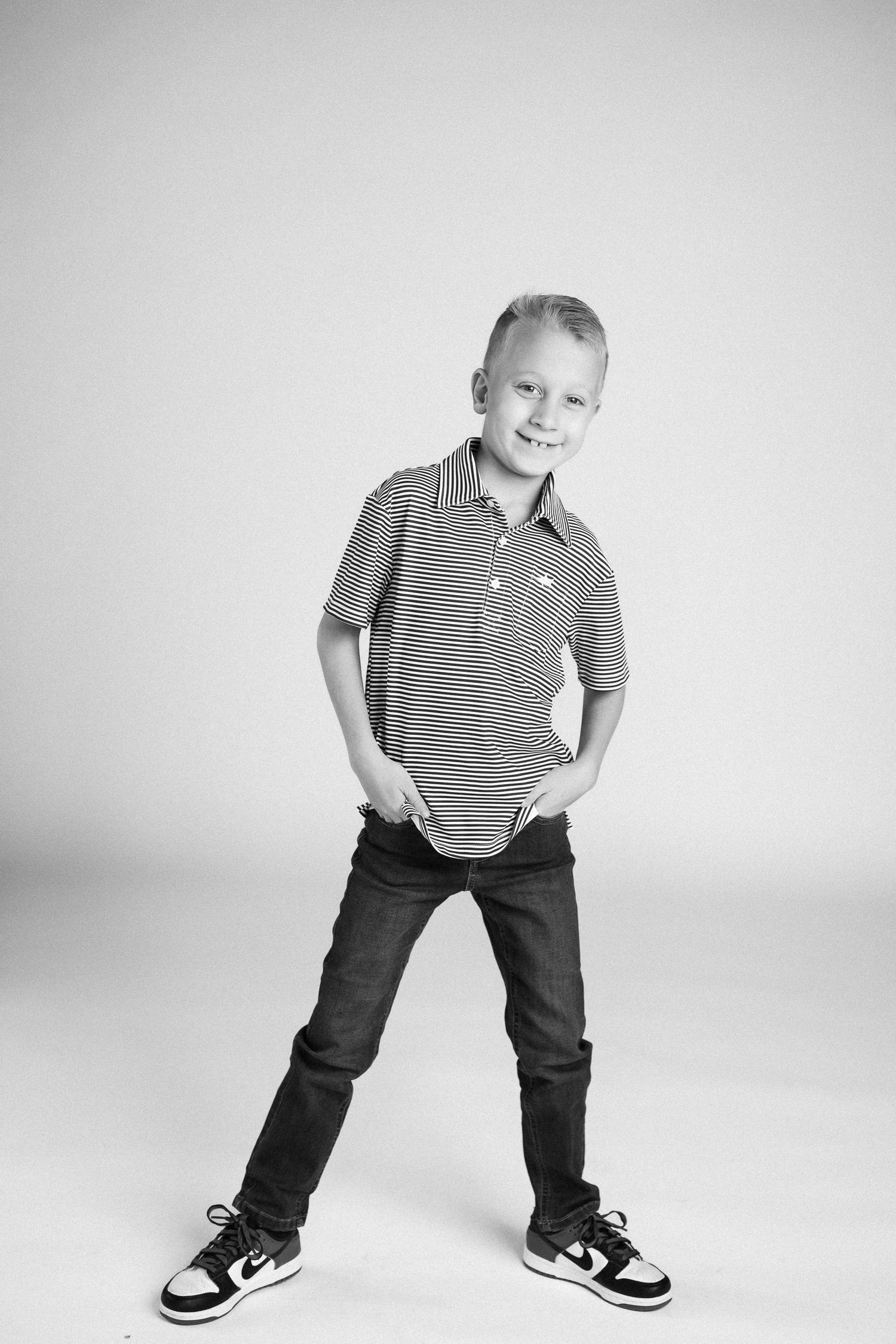 Black and white photos of a child in striped polo and dark pants striking different playful poses.