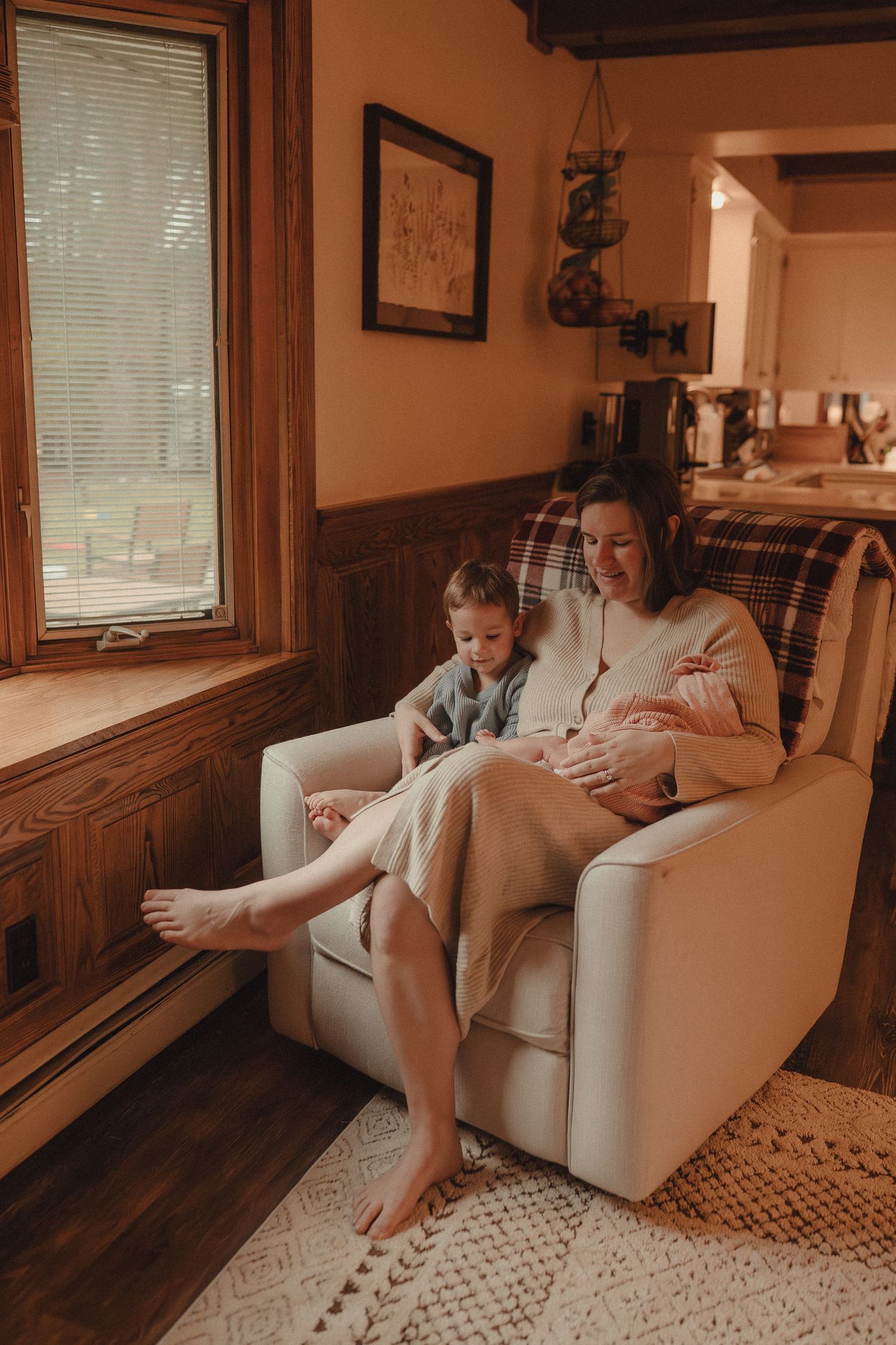 Cozy living room scene with people relaxing on a cream colored couch near windows with natural light.