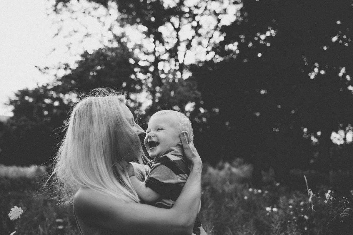 A joyful black and white portrait of parent and child laughing together outdoors.