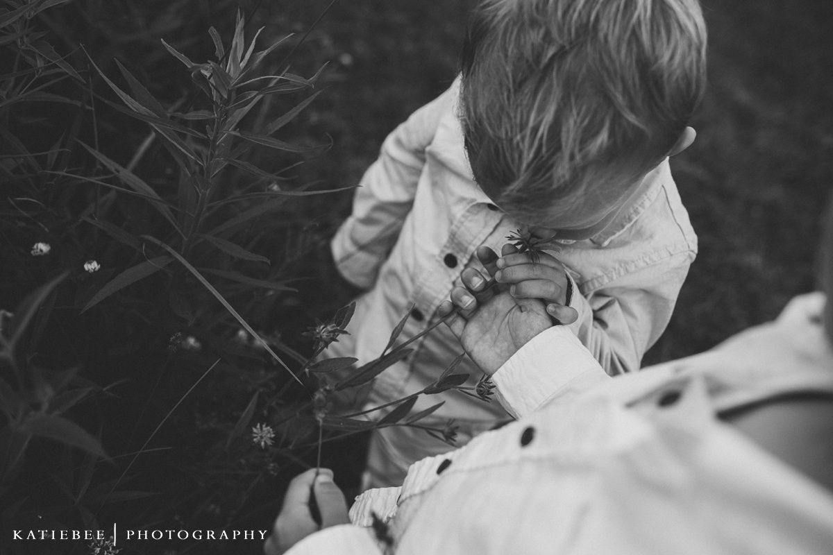 Black and white image of child exploring plants and nature outdoors.