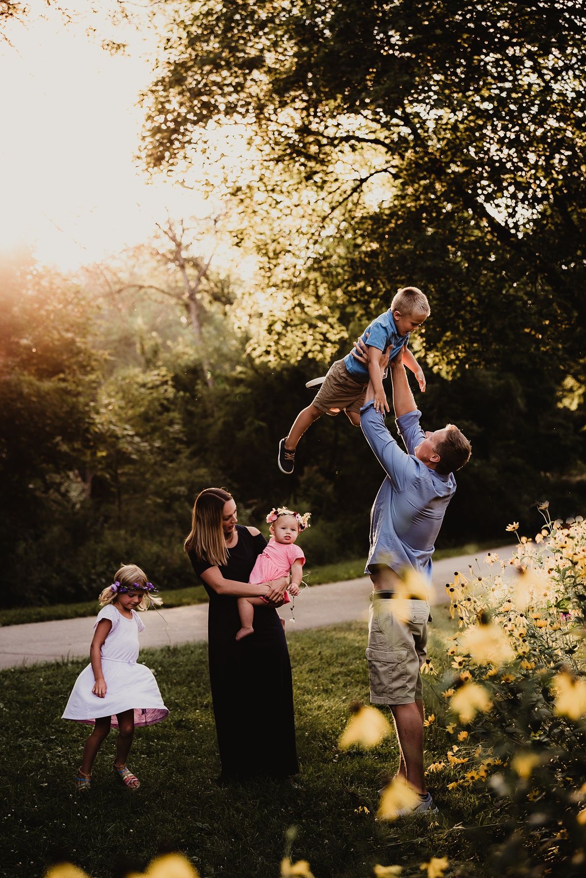 A joyful family photo session at sunset with sunlight bokeh and trees in the background.