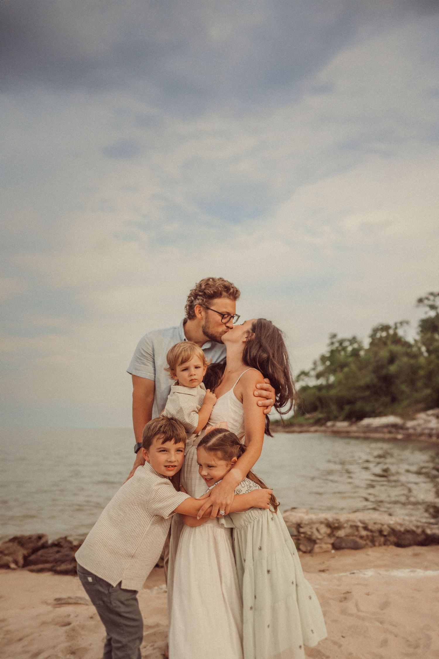 A loving family shares an intimate moment together on a beach during golden hour.