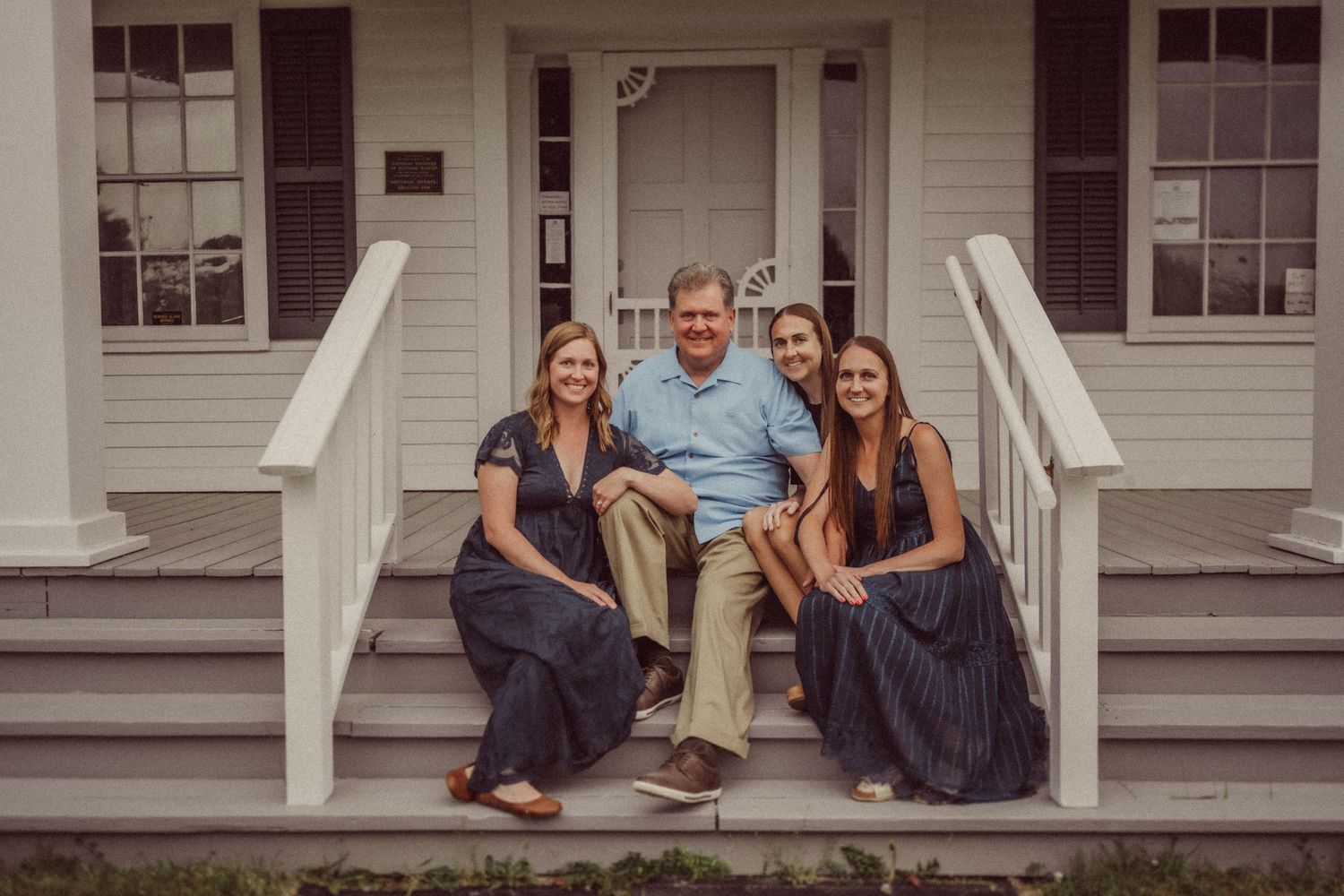 Family portrait on white porch steps of colonial style house.