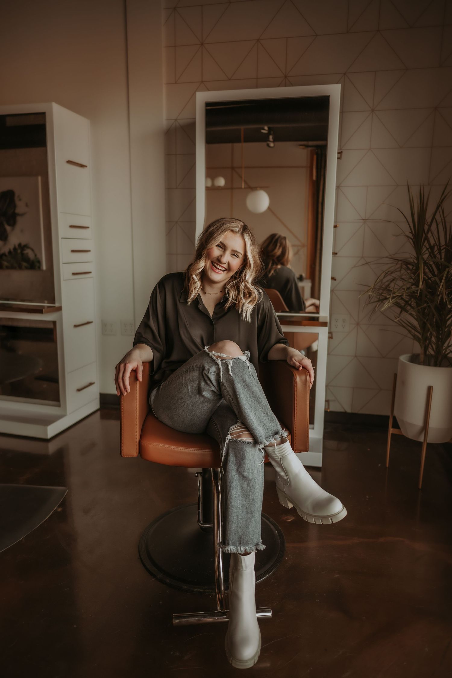Relaxed portrait in salon chair with industrial-chic background and warm lighting.