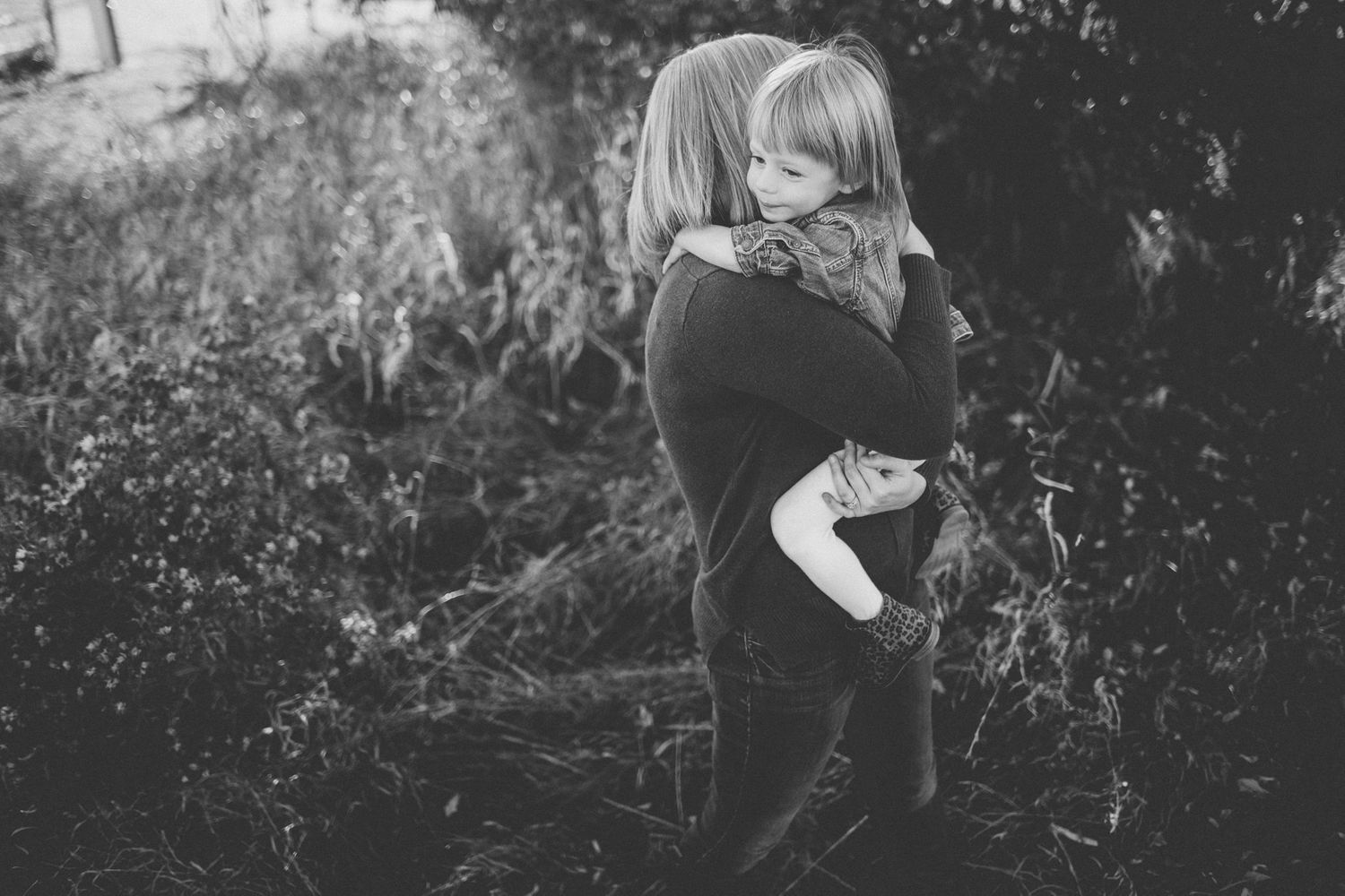 Black and white image of two people embracing in a natural outdoor setting.