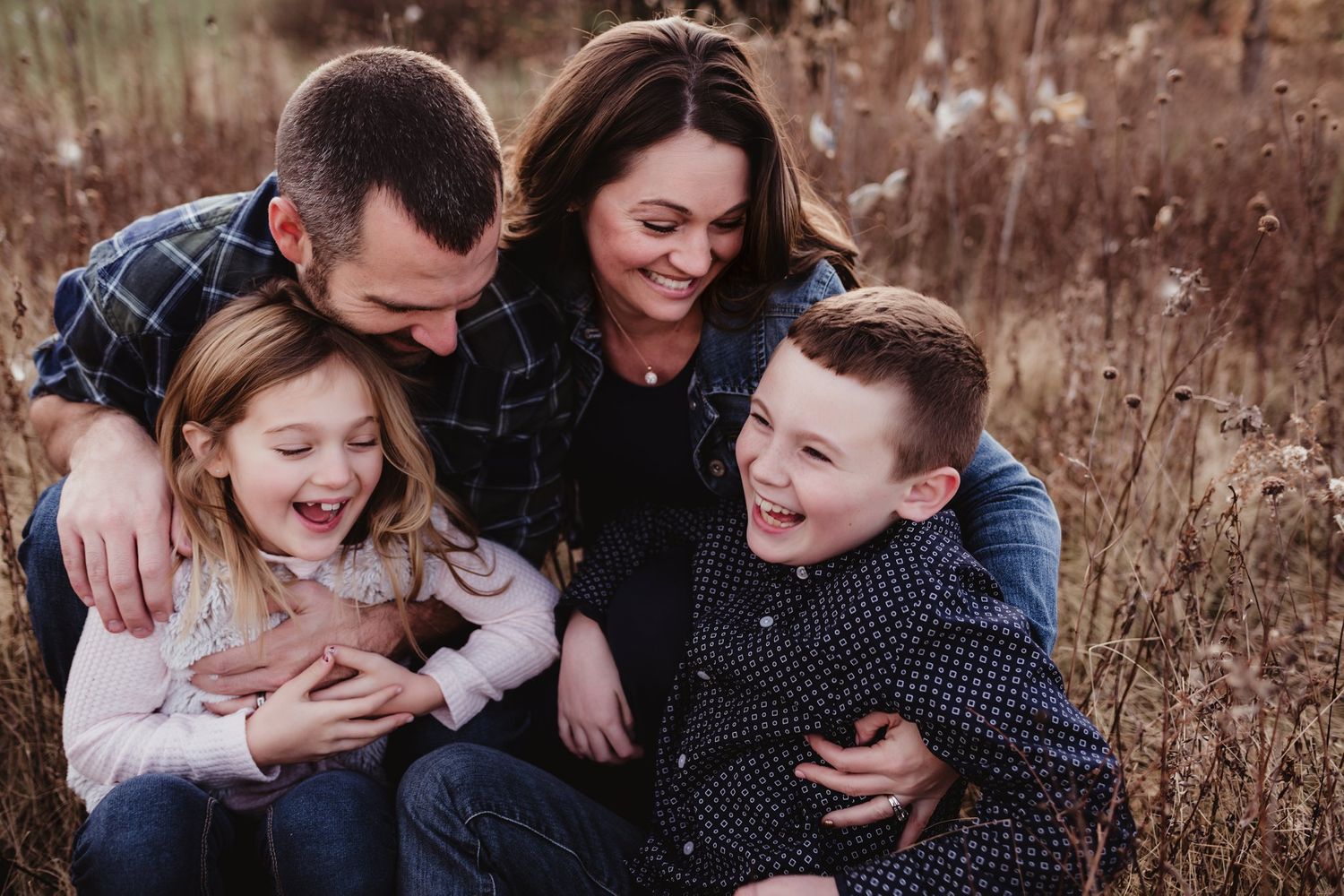 A candid family moment full of laughter and joy in an outdoor setting.