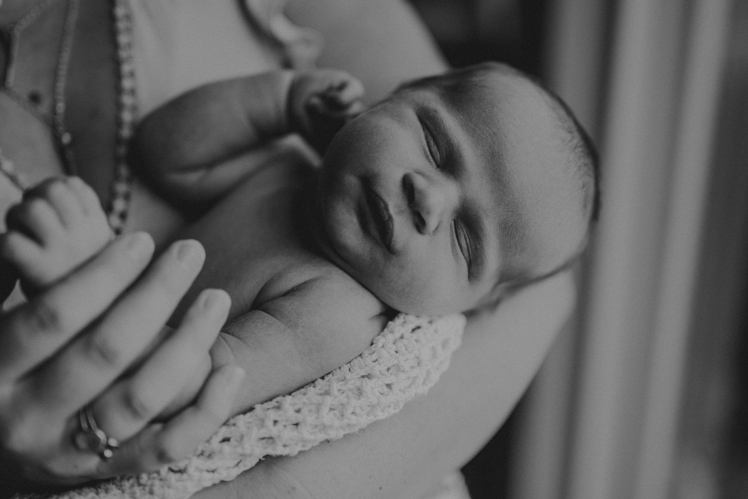 Close-up black and white portrait of peaceful sleeping newborn wrapped in lace.