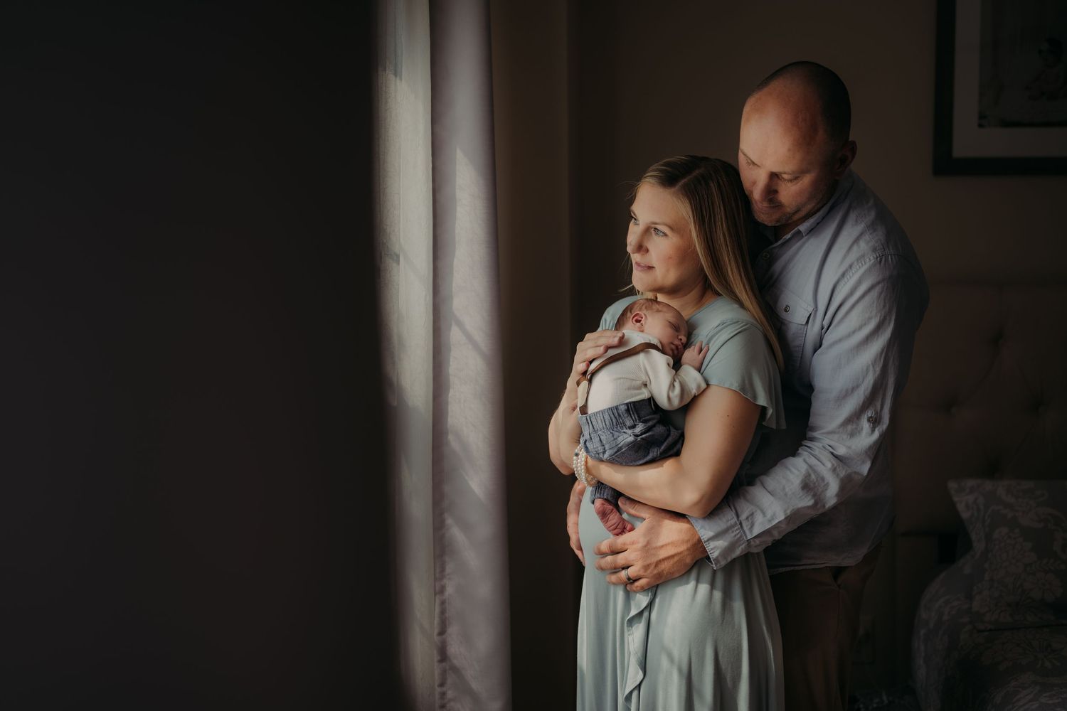 A tender embrace between a couple standing by a window in soft natural light.