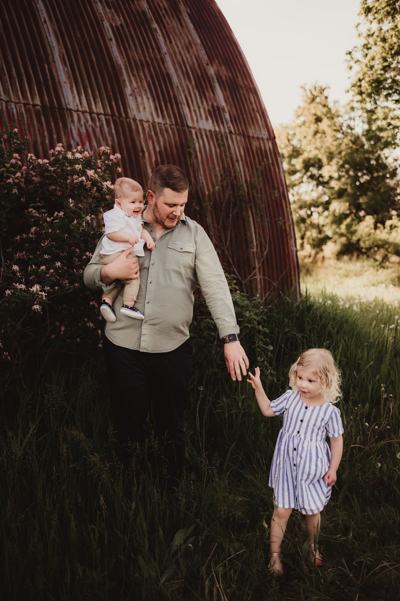 A heartwarming family moment captured outside a rustic barn in golden evening light.