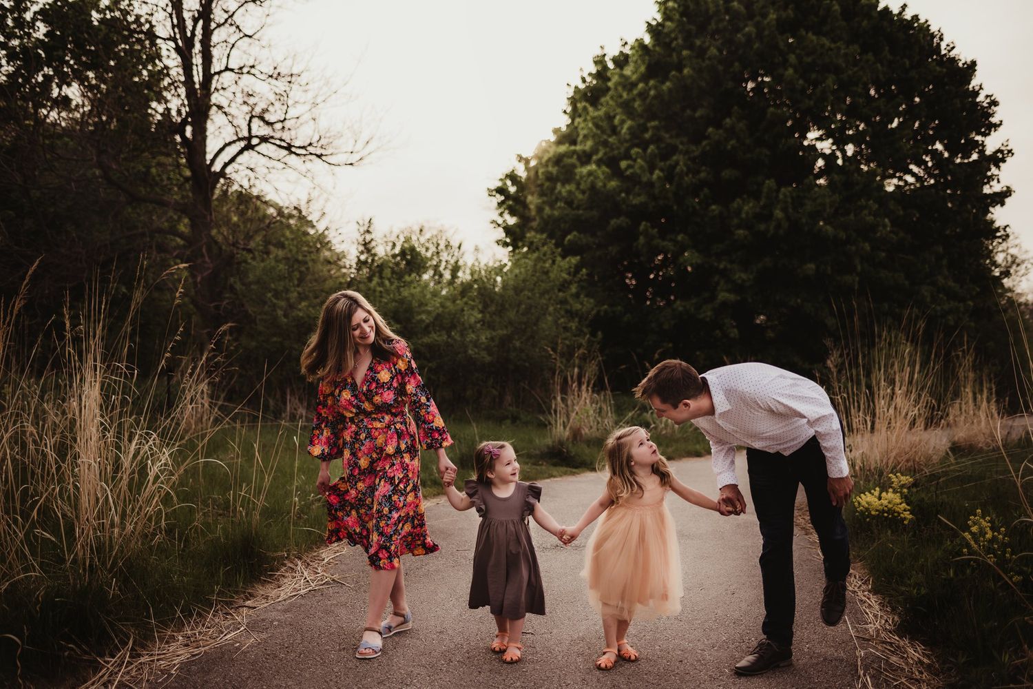 A family walks hand in hand down a nature path at sunset while wearing formal attire.
