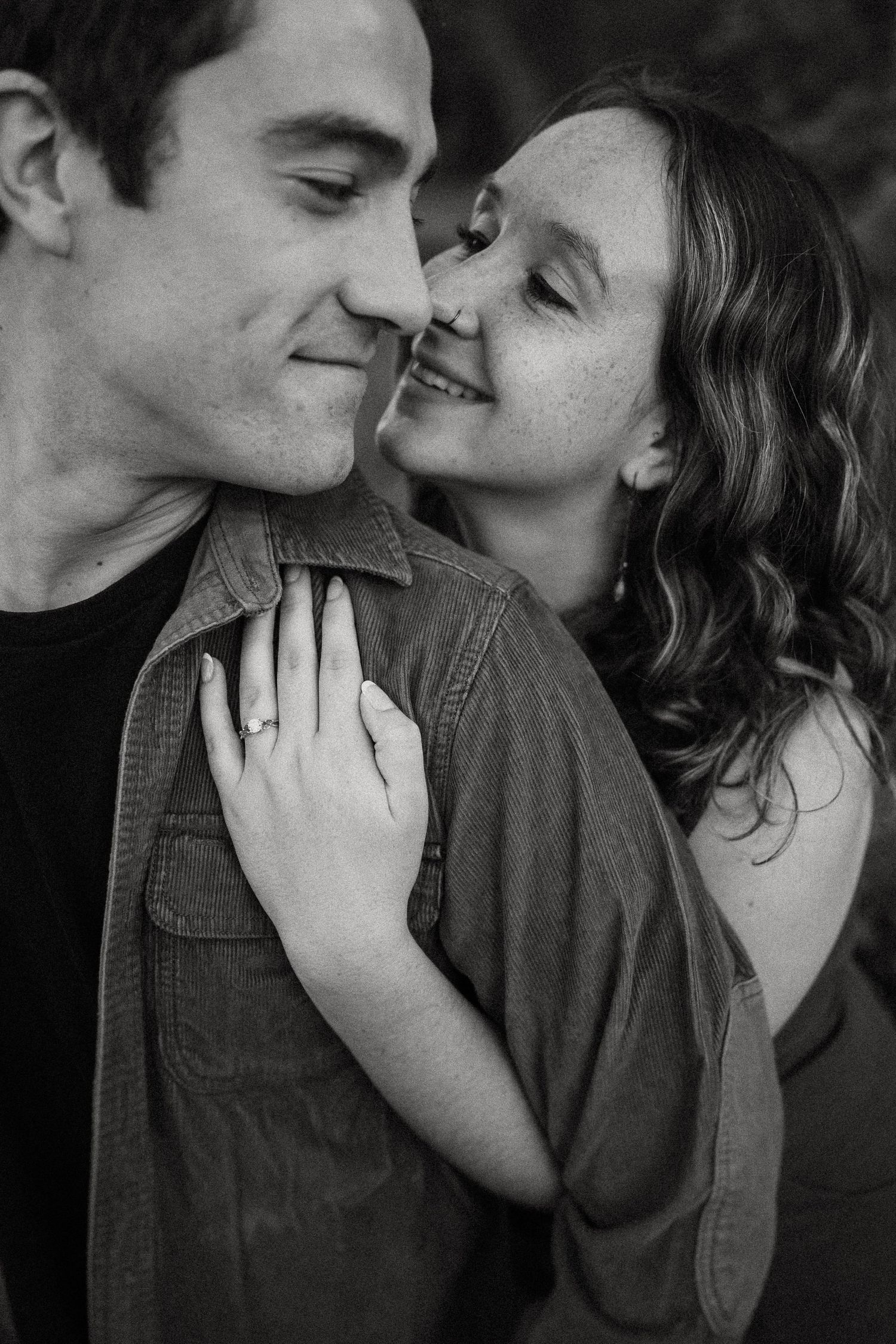 An intimate black and white portrait of a couple sharing a close moment.