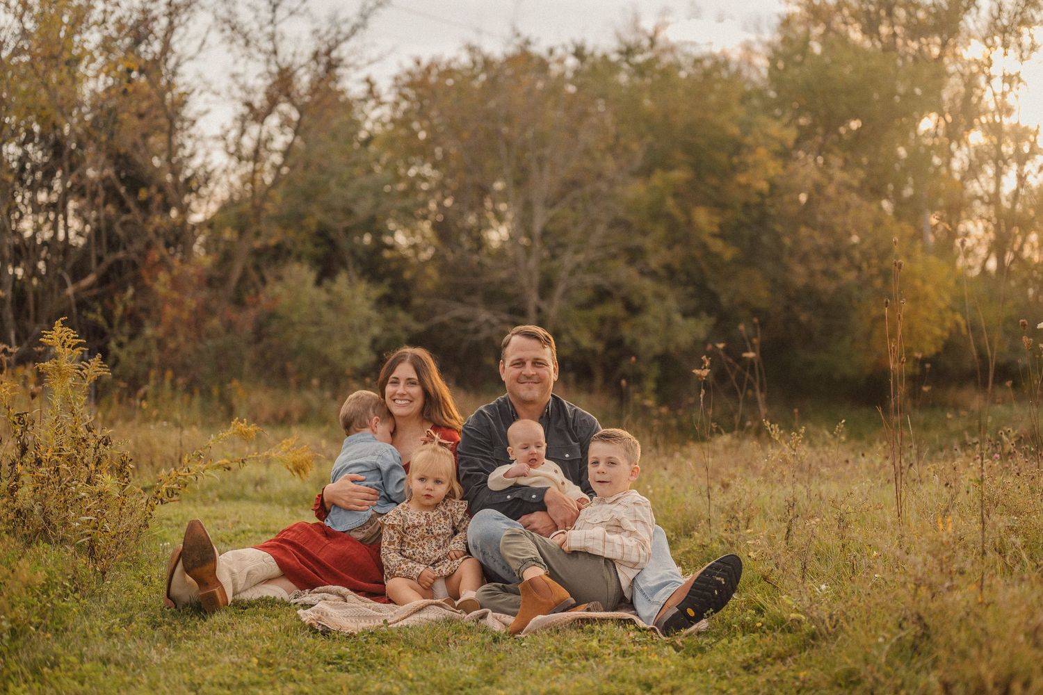 People enjoying quality time together on blankets in a grassy field during sunset.