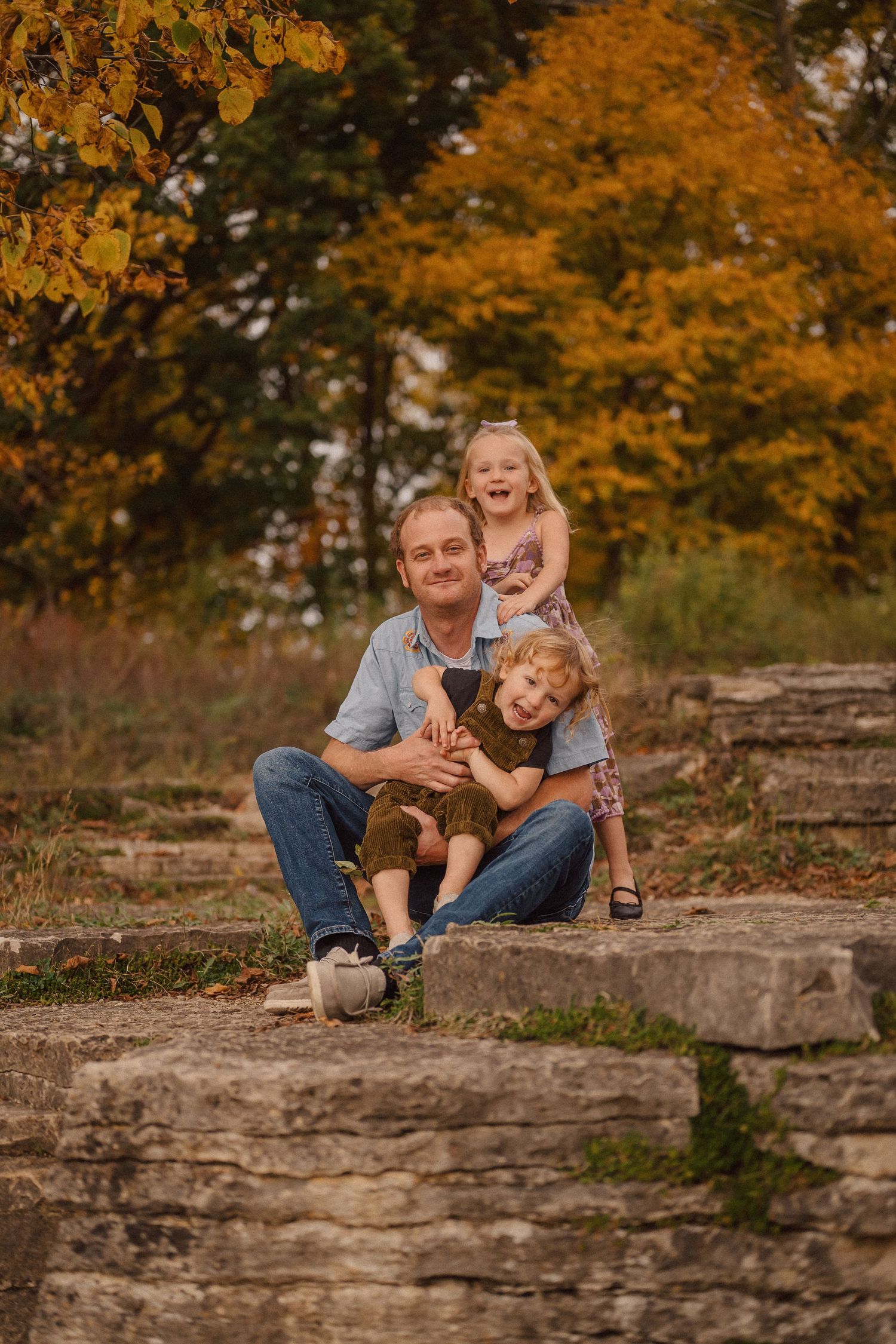A heartwarming family scene with a puppy on stone steps amid fall colors.