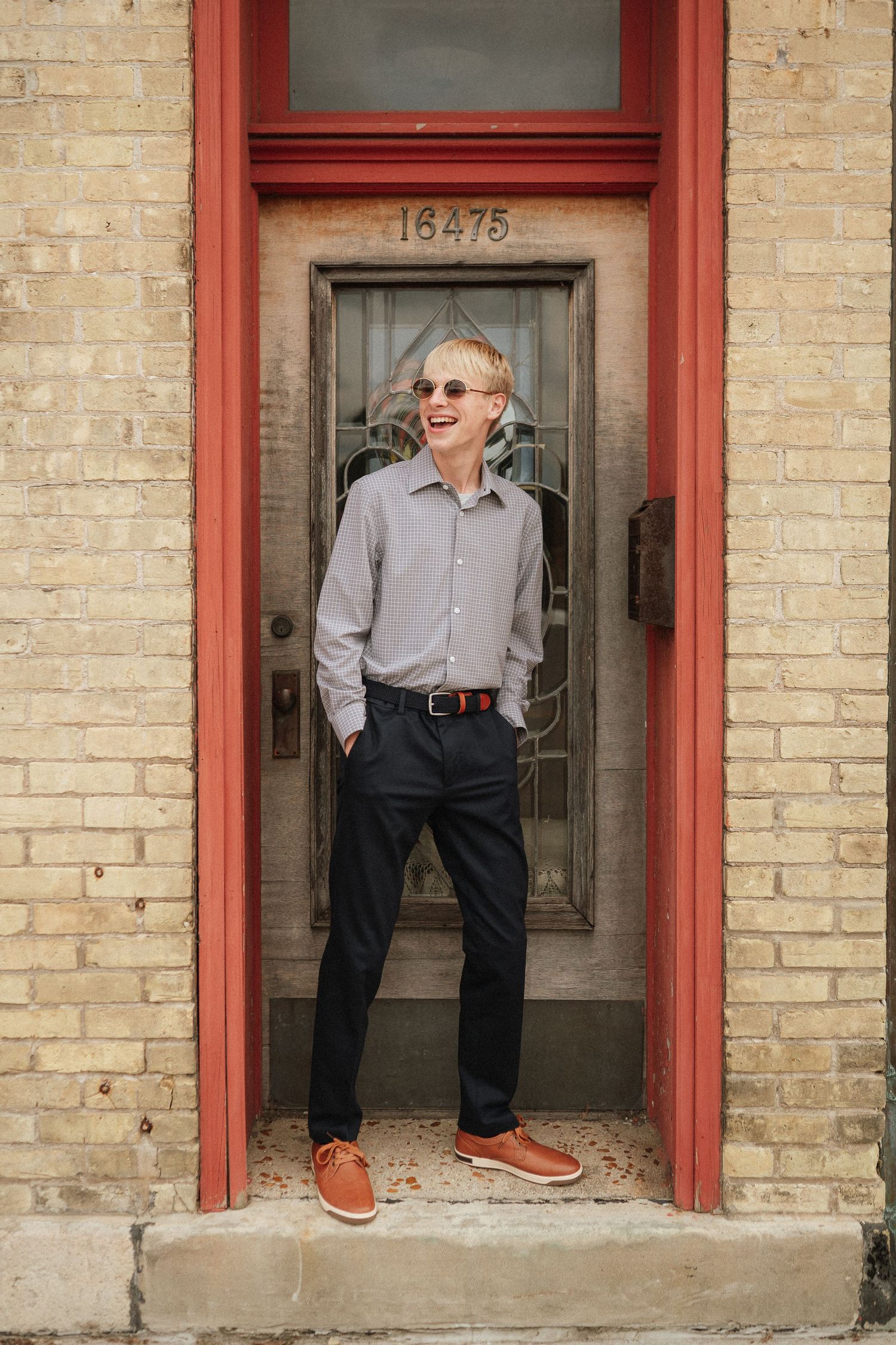 A series of candid poses against a brick wall with red doorframes showing playful expressions and casual style.