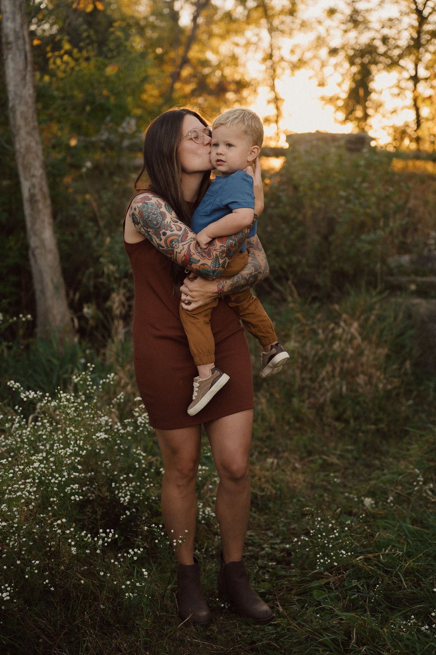 Parent and child sharing affectionate moment in outdoor setting during sunset.