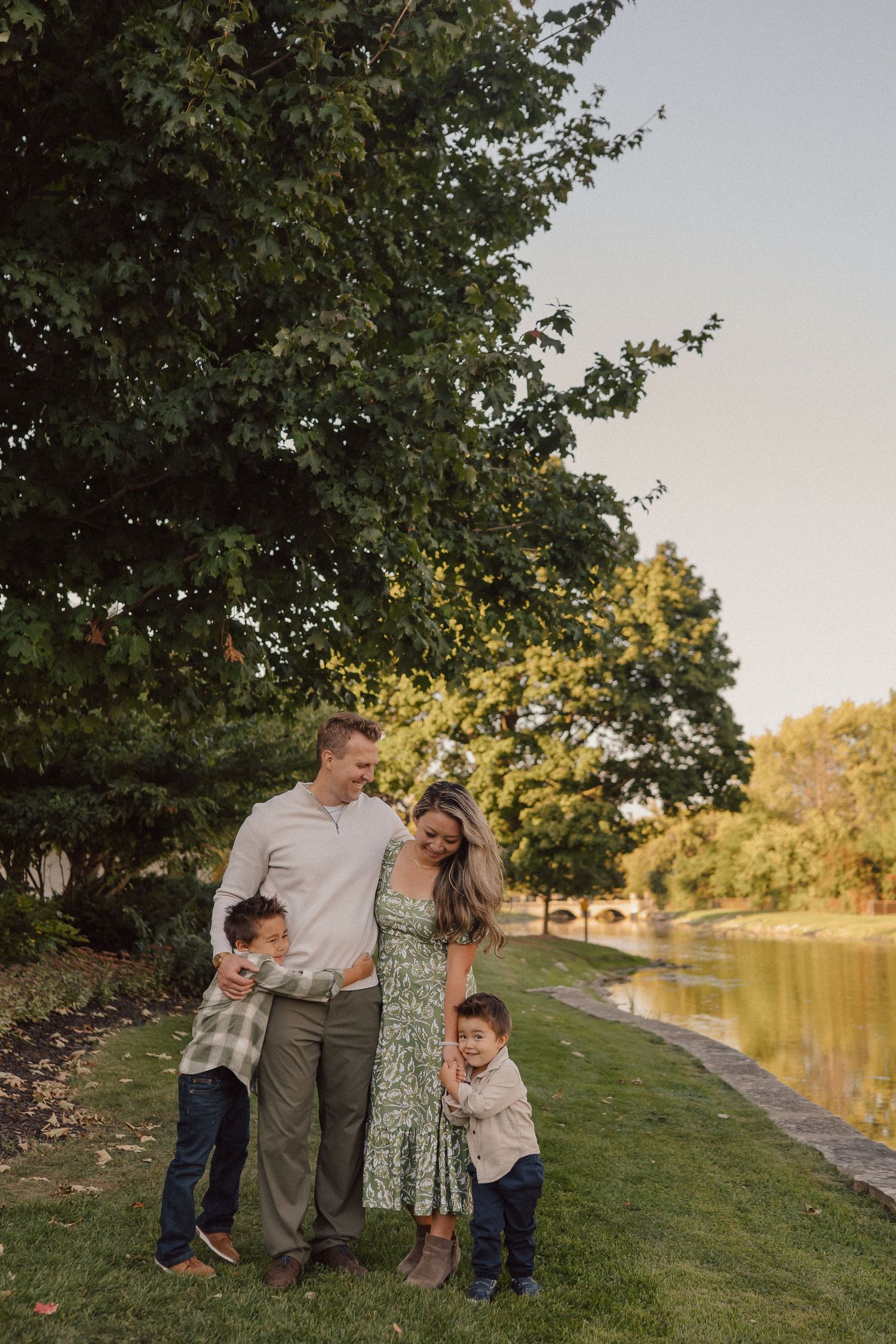 A family enjoys a candid moment of laughter and connection while spending time outdoors by a lake at sunset.
