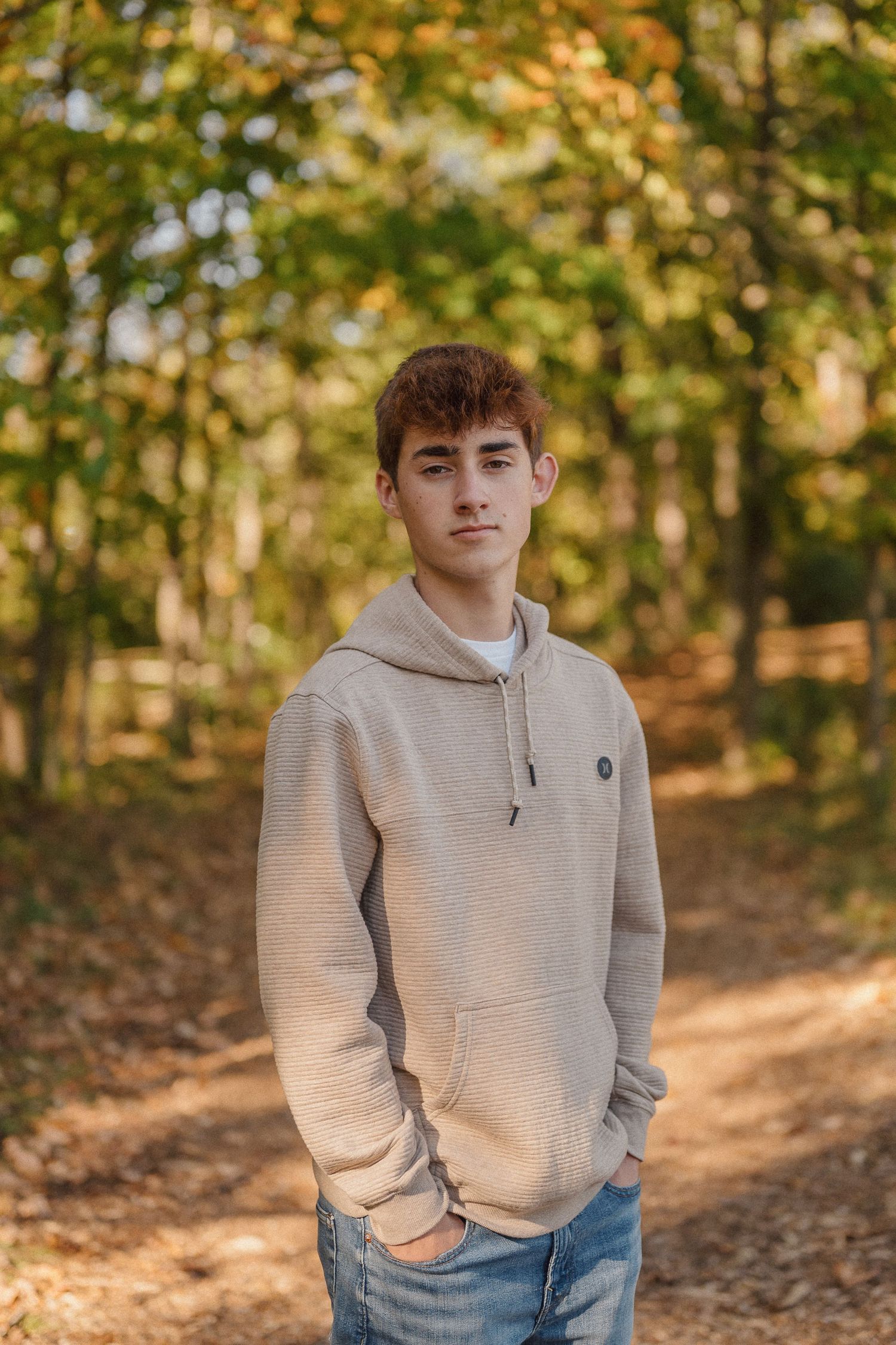 Casual autumn portrait in a wooded setting with golden leaves and natural lighting.