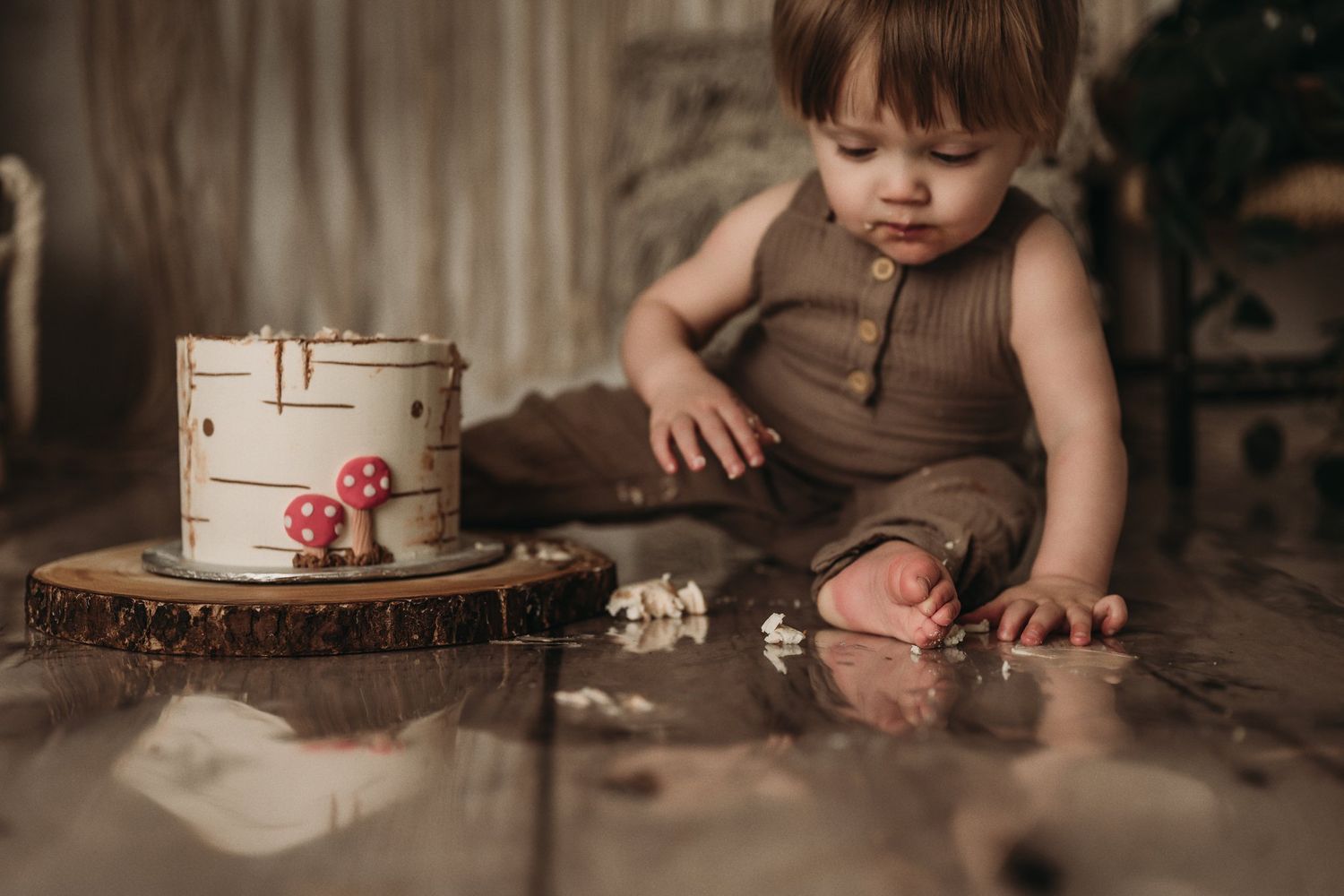 A white birch-patterned cake with red mushroom details displayed on rustic wooden cake stand.