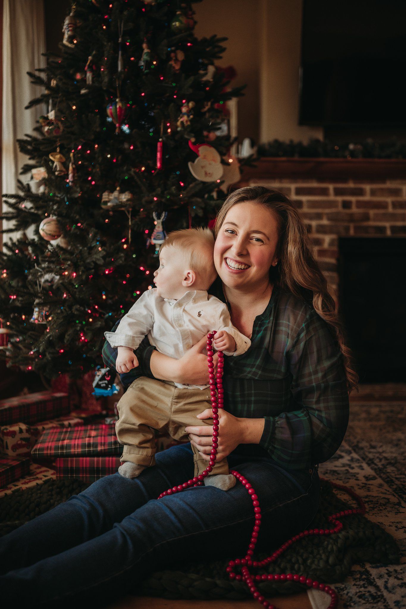 A warm moment by a decorated Christmas tree with red beads and ornaments on a patterned rug.