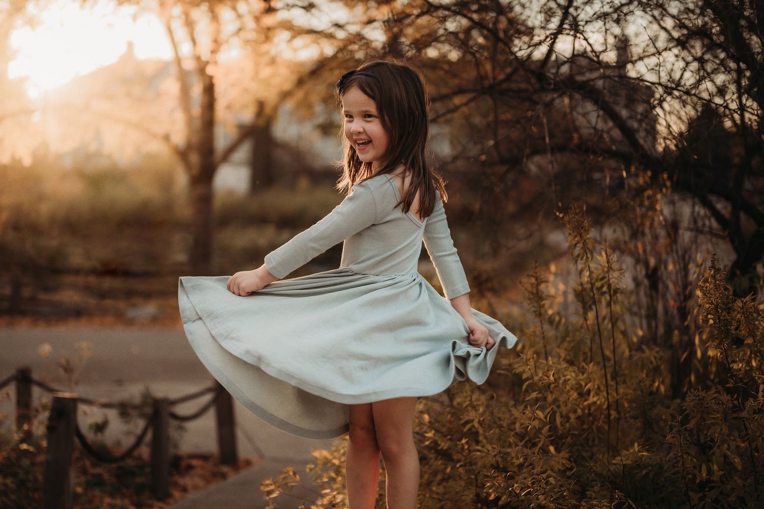 A playful twirling dress movement captured at golden hour in a park setting.