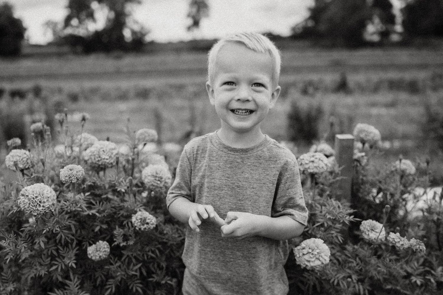 Black and white portrait surrounded by blooming flowers in a garden setting.