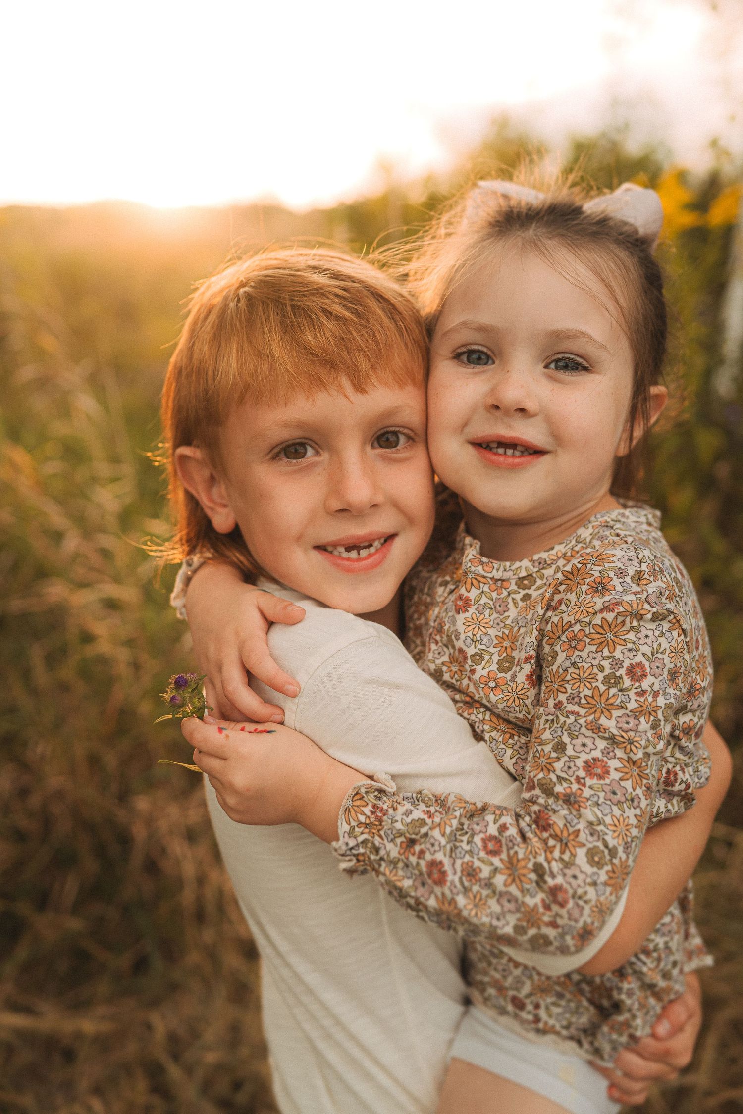 Two children hugging and smiling in golden sunlight.