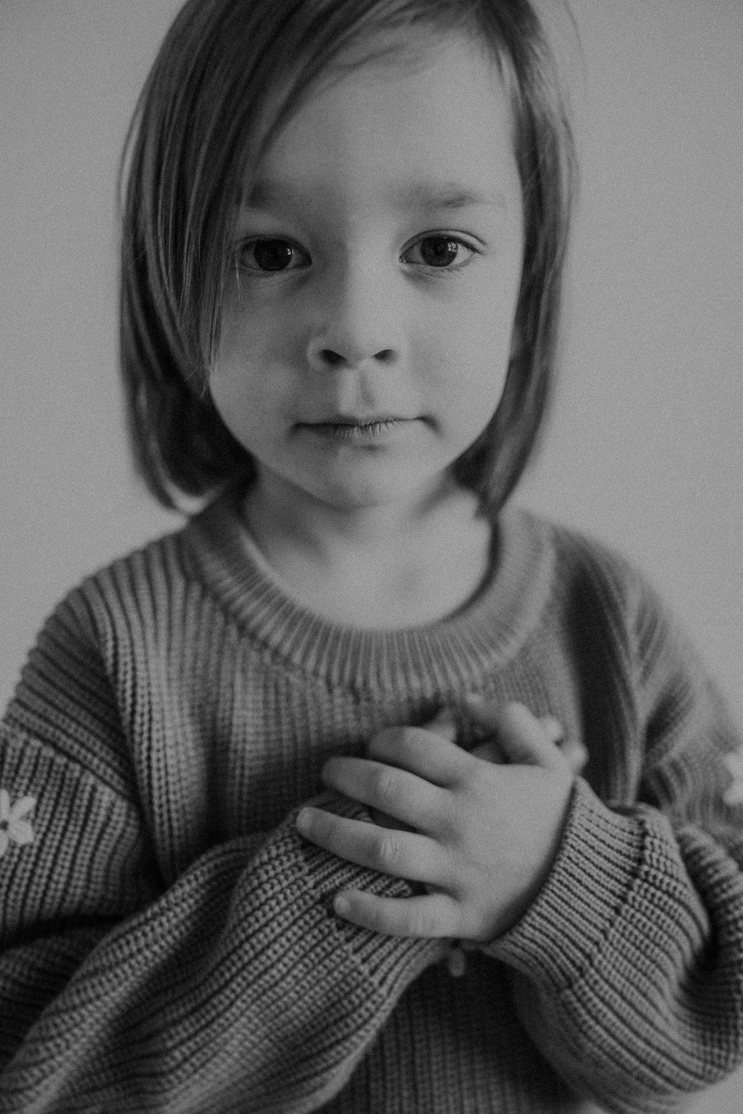 Tender black and white portrait showing thoughtful expression with hand over heart.