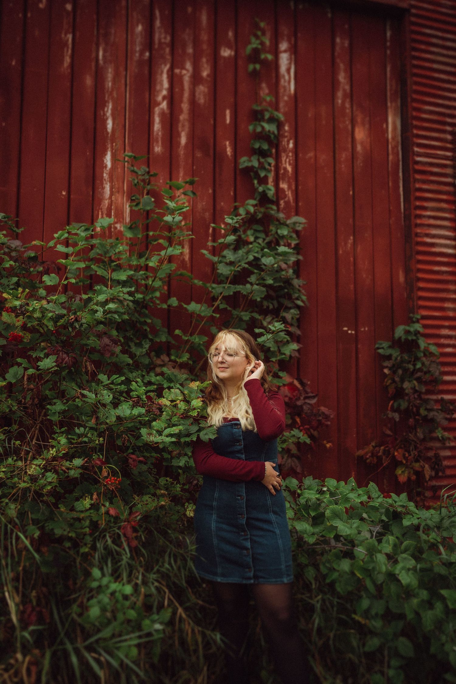 A joyful outdoor portrait against weathered red barn siding surrounded by climbing vines.