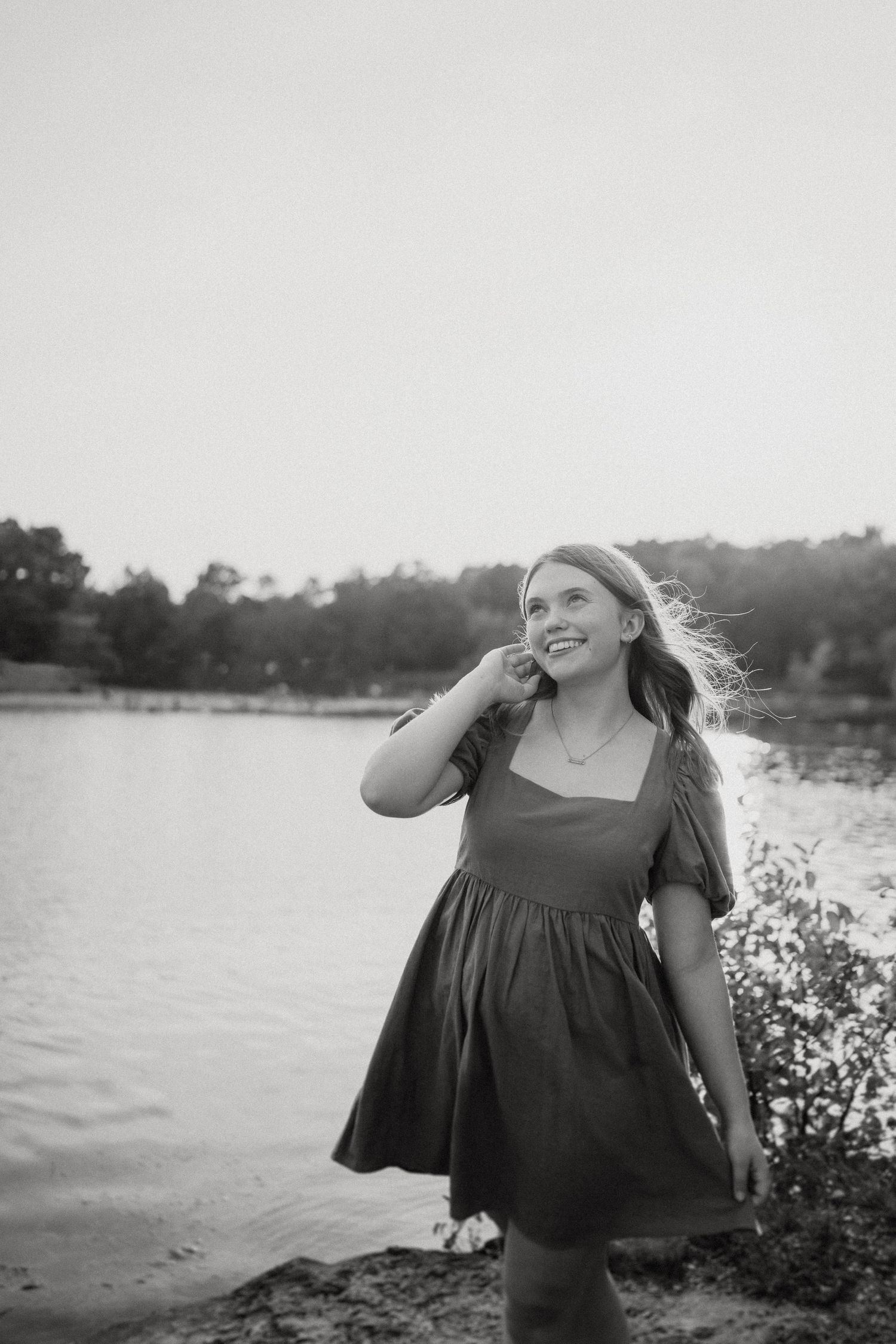 A black and white candid moment captured by the lake showing movement and joy.