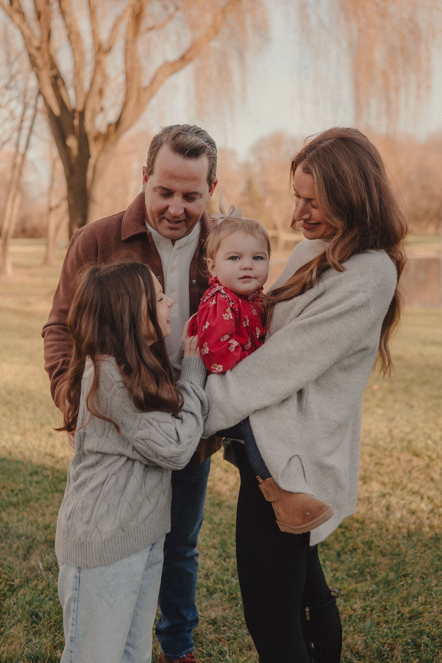 A family shares a tender moment together outdoors during autumn with warm lighting and fall foliage in the background.