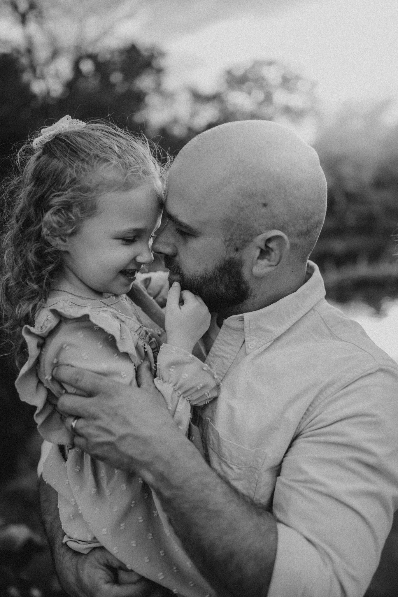An intimate black and white portrait capturing a joyful moment between parent and child.