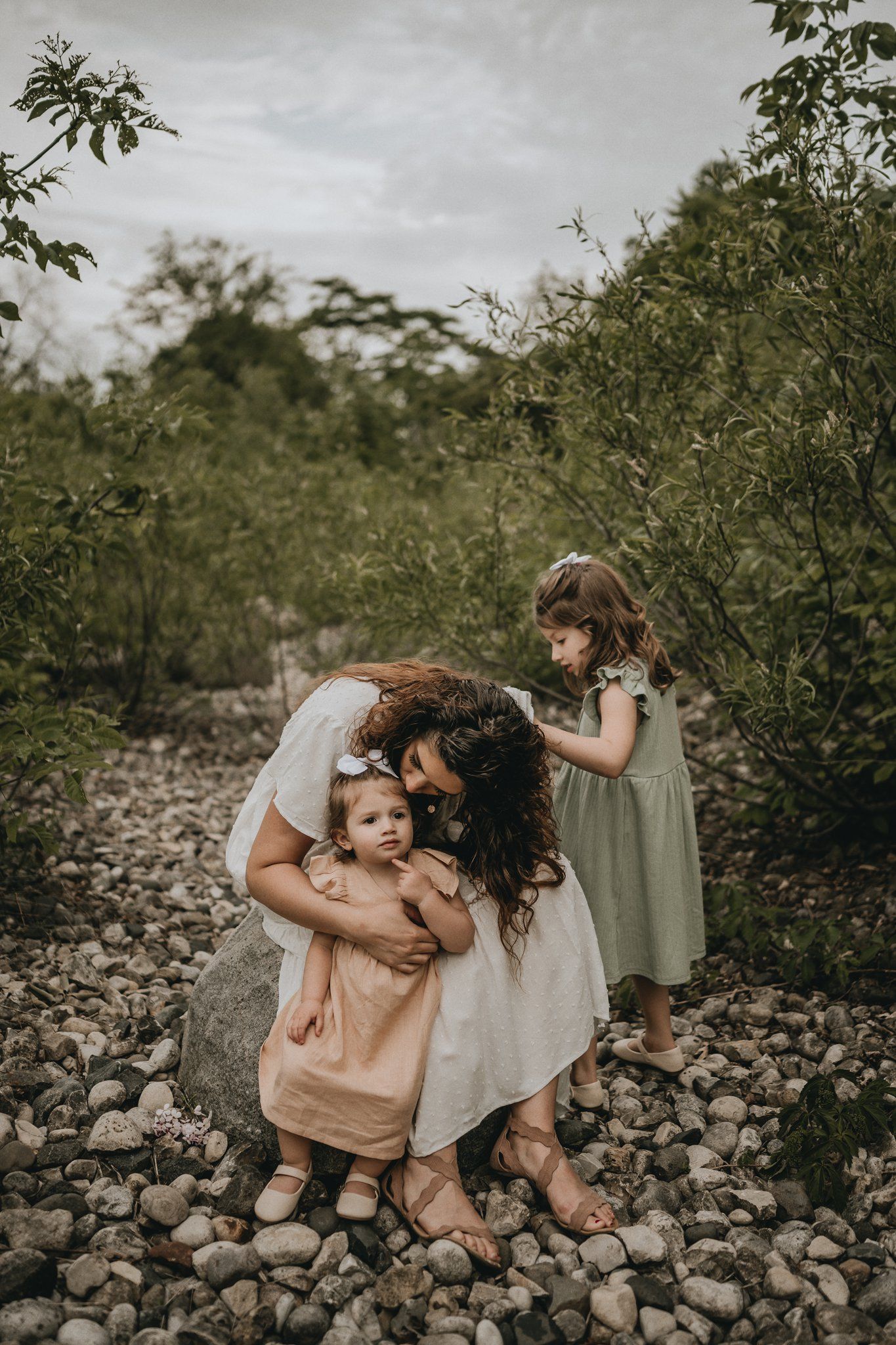 A candid family moment captured on rocky terrain surrounded by lush greenery.