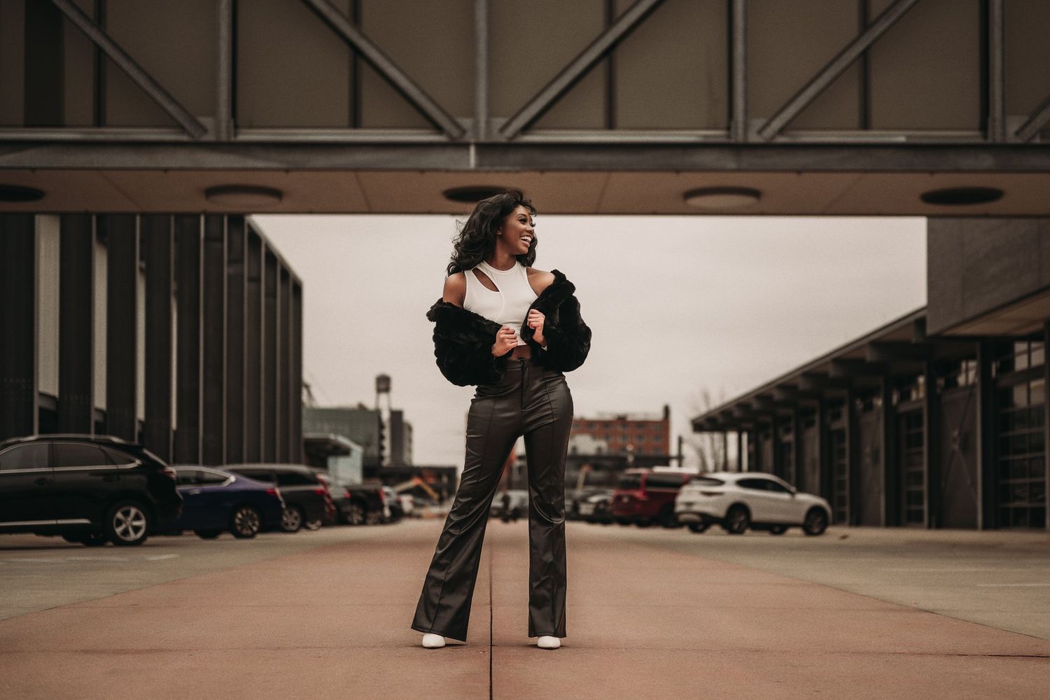 A street style photo of a model in flared pants and black jacket in an urban setting.