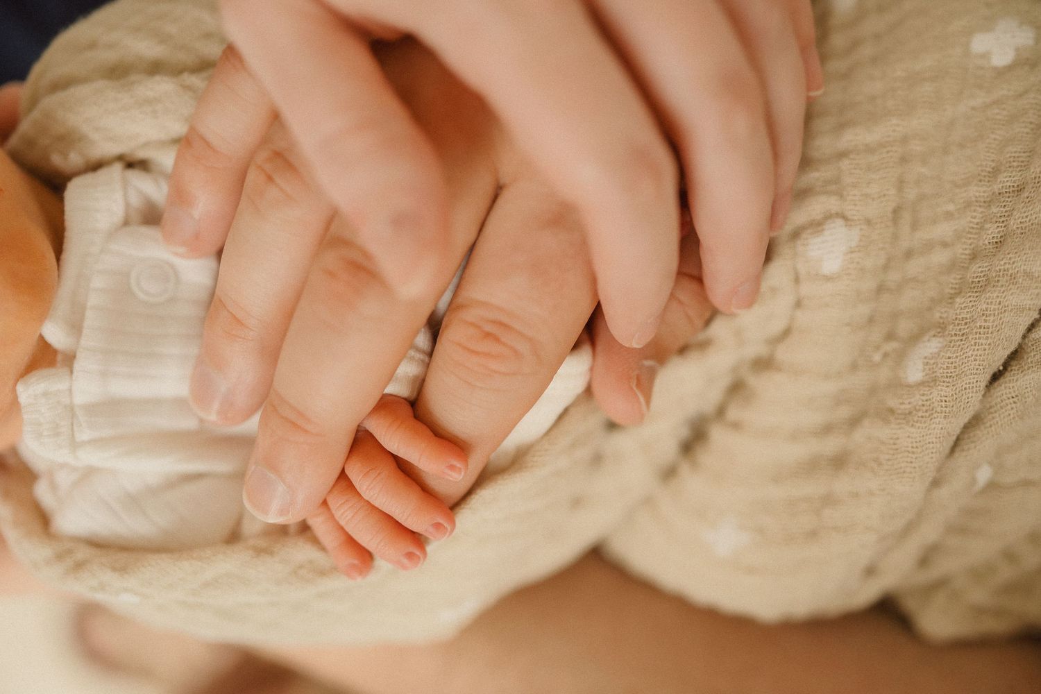 Close-up of tiny newborn baby feet wrapped in soft white knit blanket.