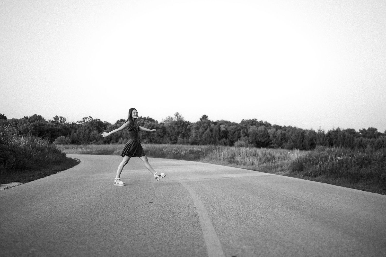 Minimalist black and white perspectives of a solitary dancer silhouetted on an empty road.