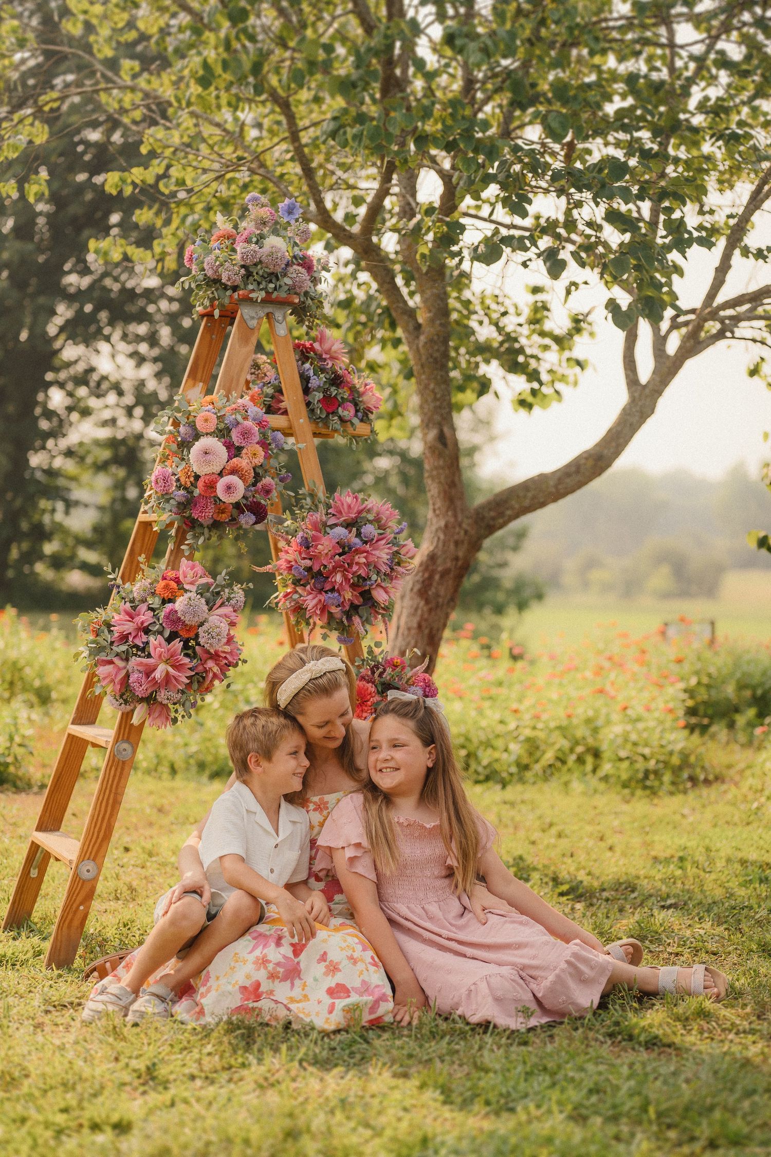 Wooden ladder decorated with pink floral arrangements creates a dreamy backdrop in a sunlit garden setting.
