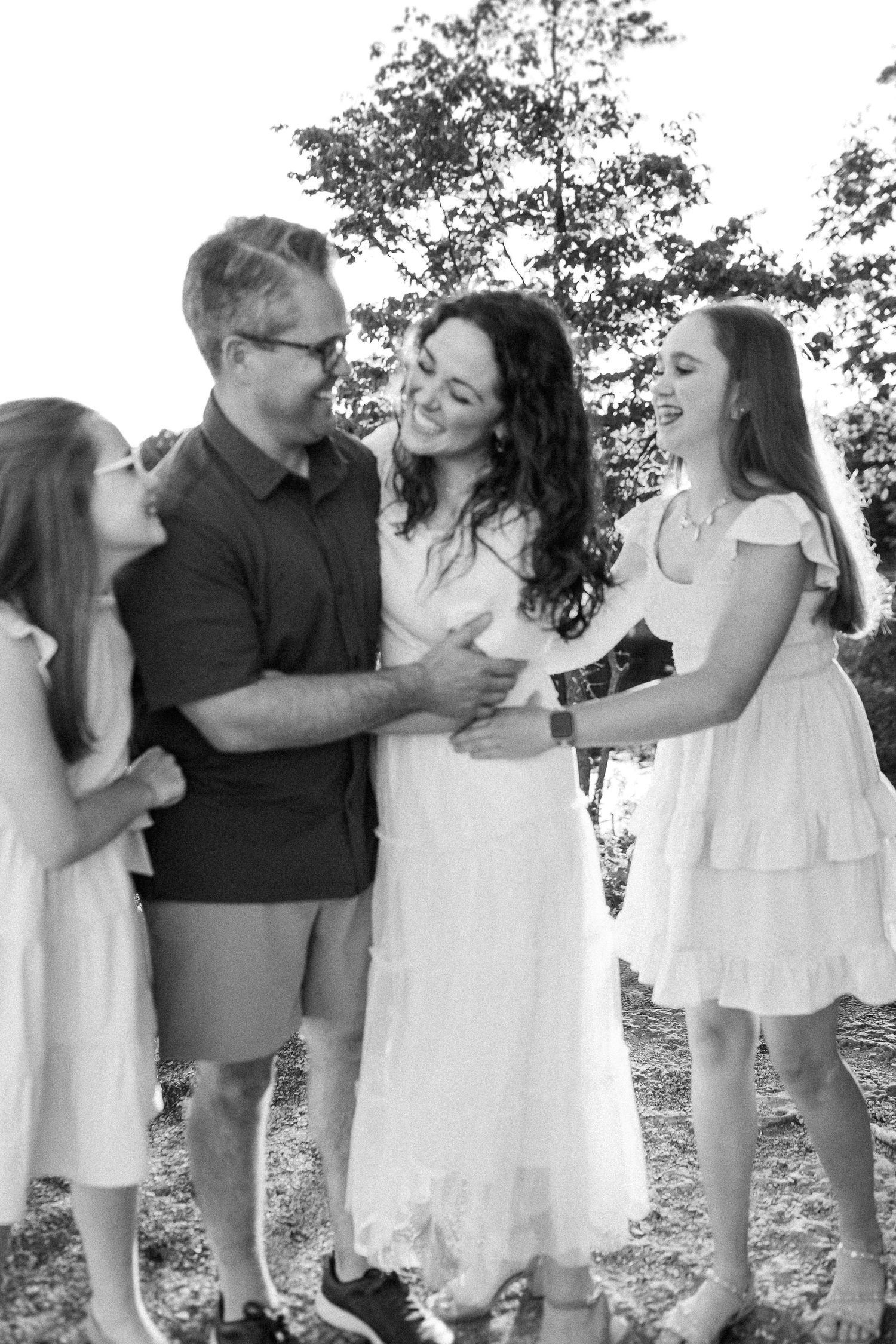 Family sharing joyful moments together in white dresses against a natural outdoor backdrop.