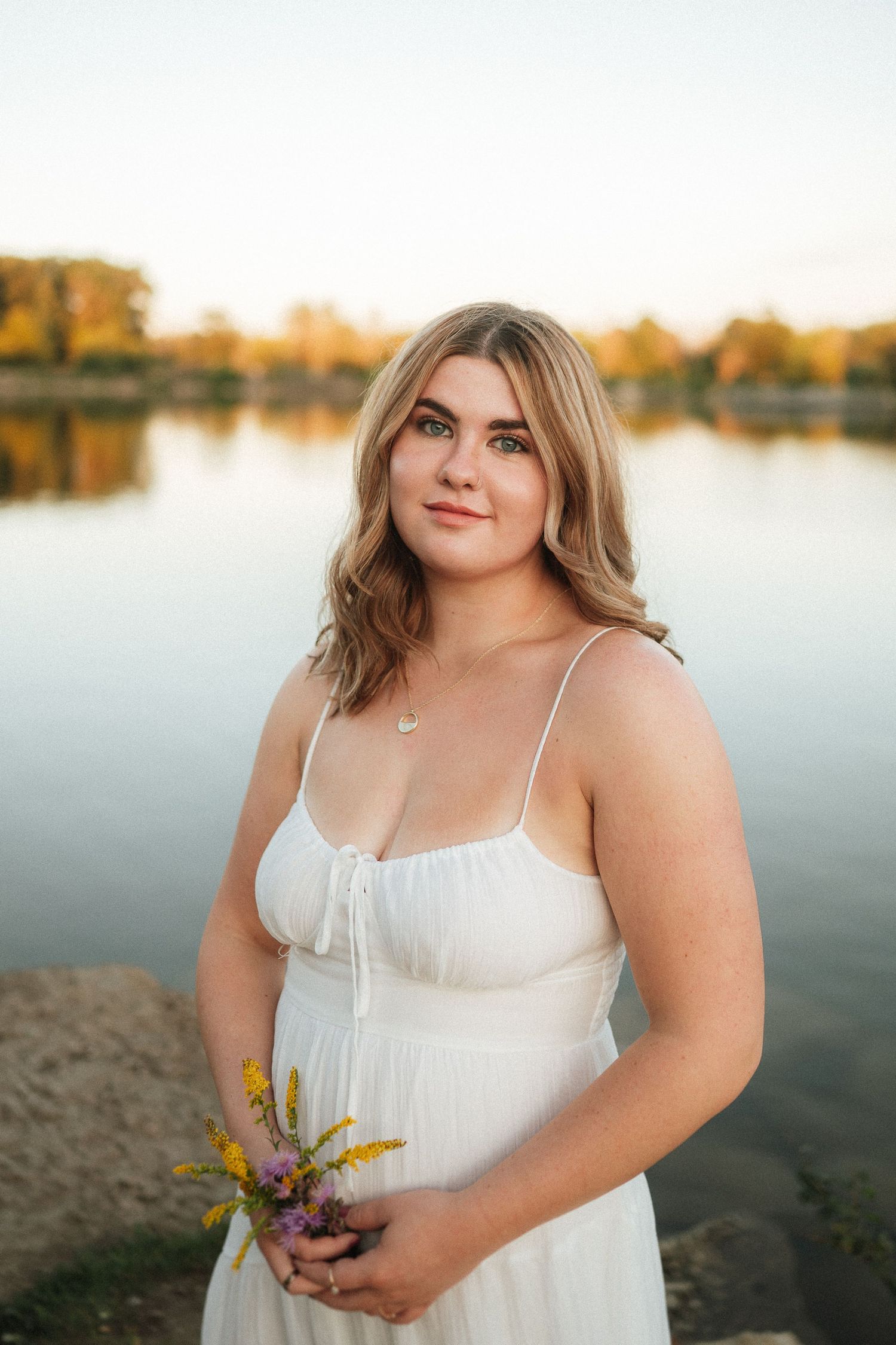 White summer dress against lakeside backdrop during sunset.