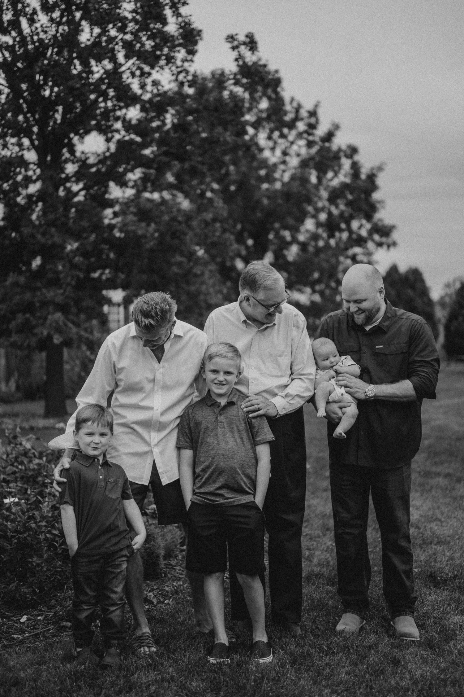 Black and white candid moment of family members sharing laughter in an outdoor garden setting.