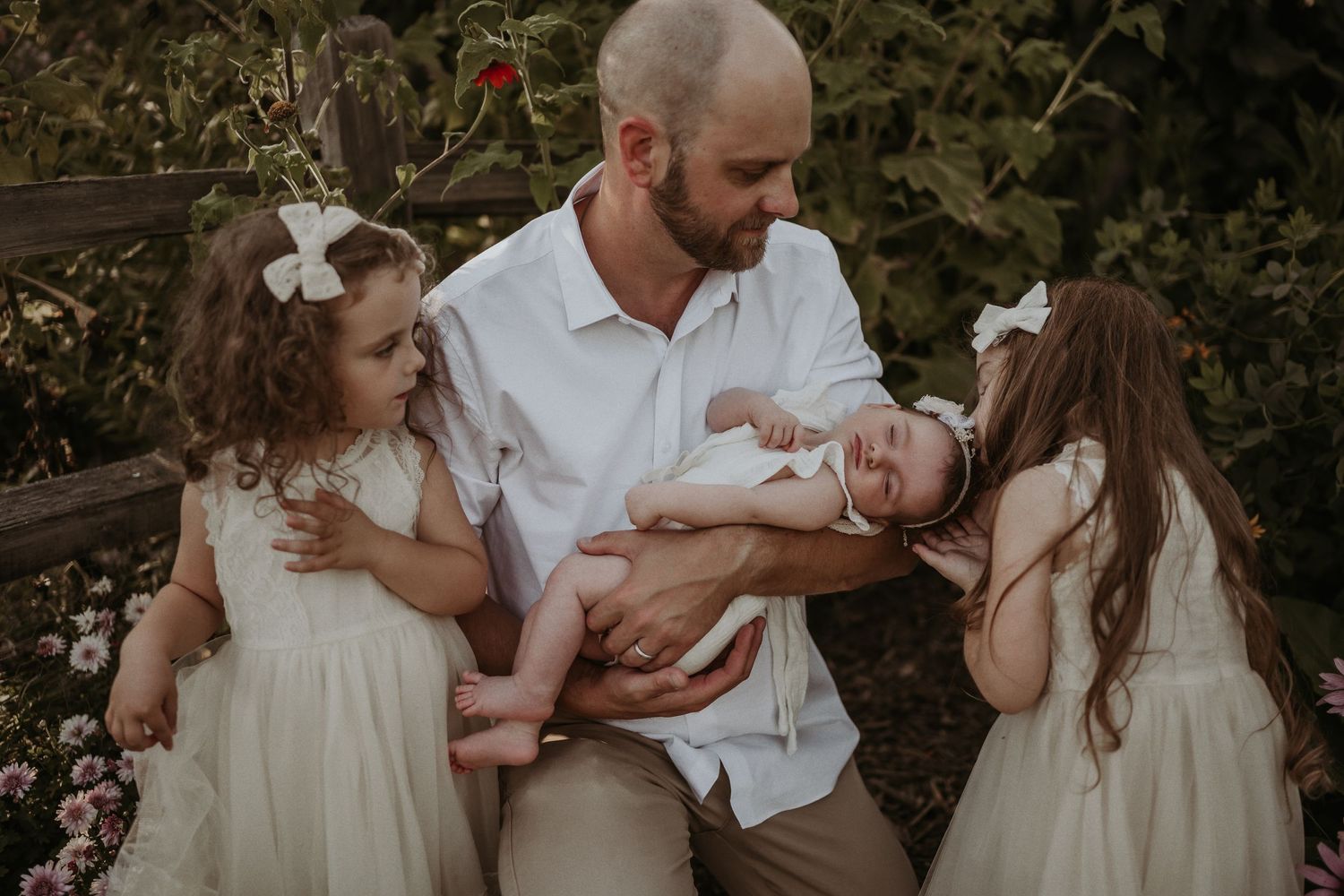 A heartwarming family scene in a garden with little ones in white dresses gathered around a parent.