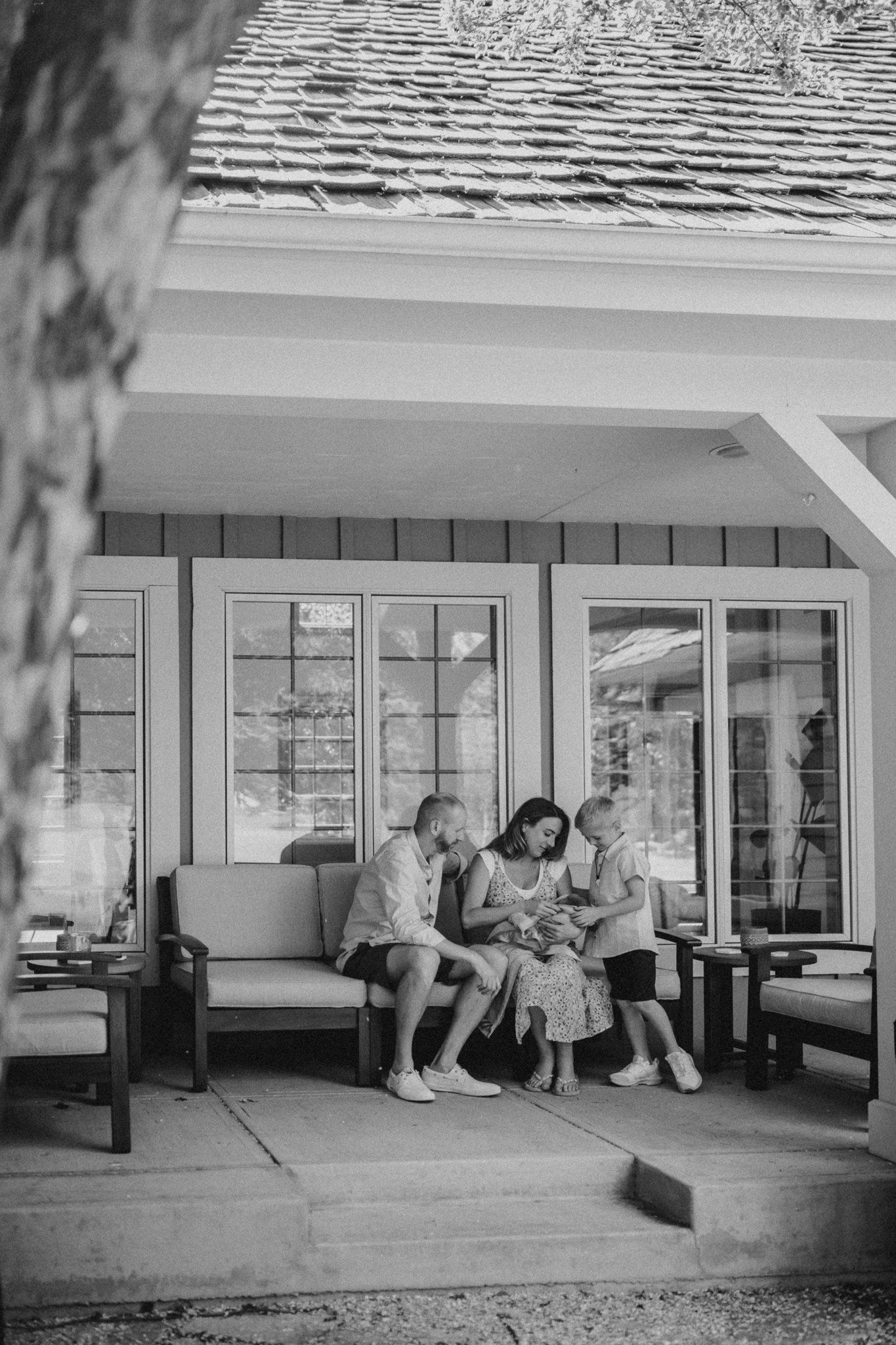 Black and white photo of family gathering on outdoor porch seating.