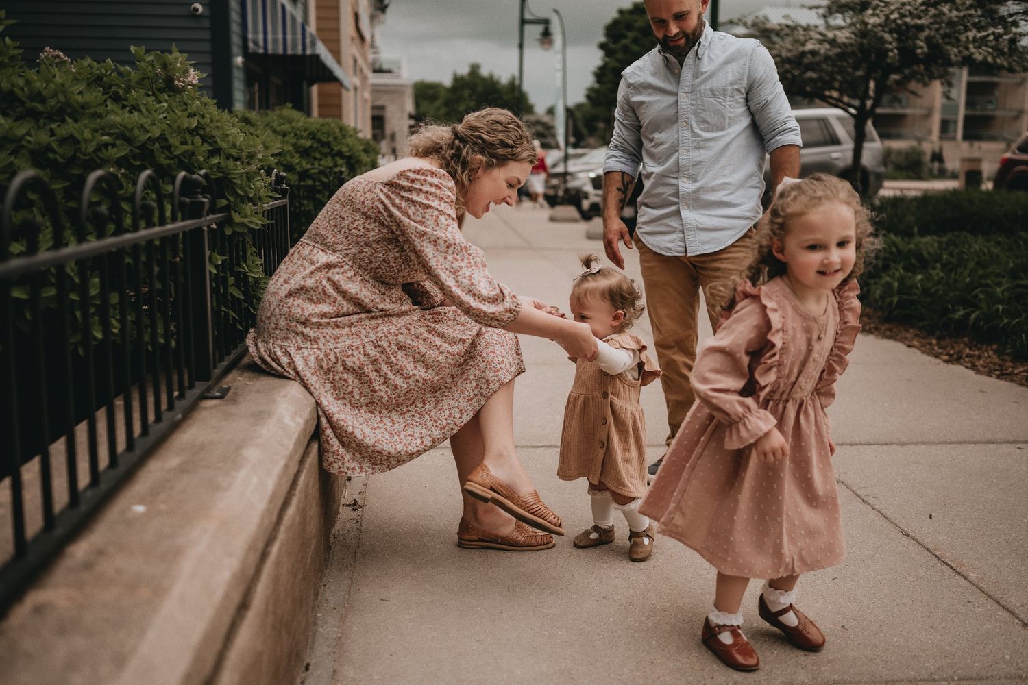 A sweet moment between family members on a city sidewalk wearing matching pink tones.
