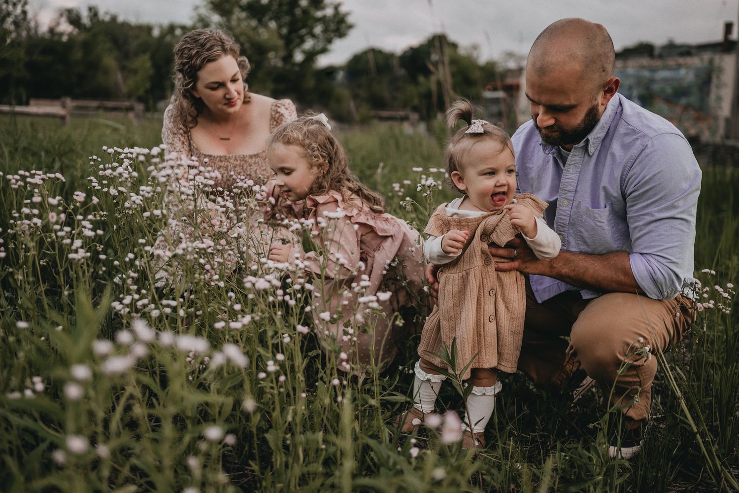 A family shares a tender moment together while sitting in a wildflower meadow.